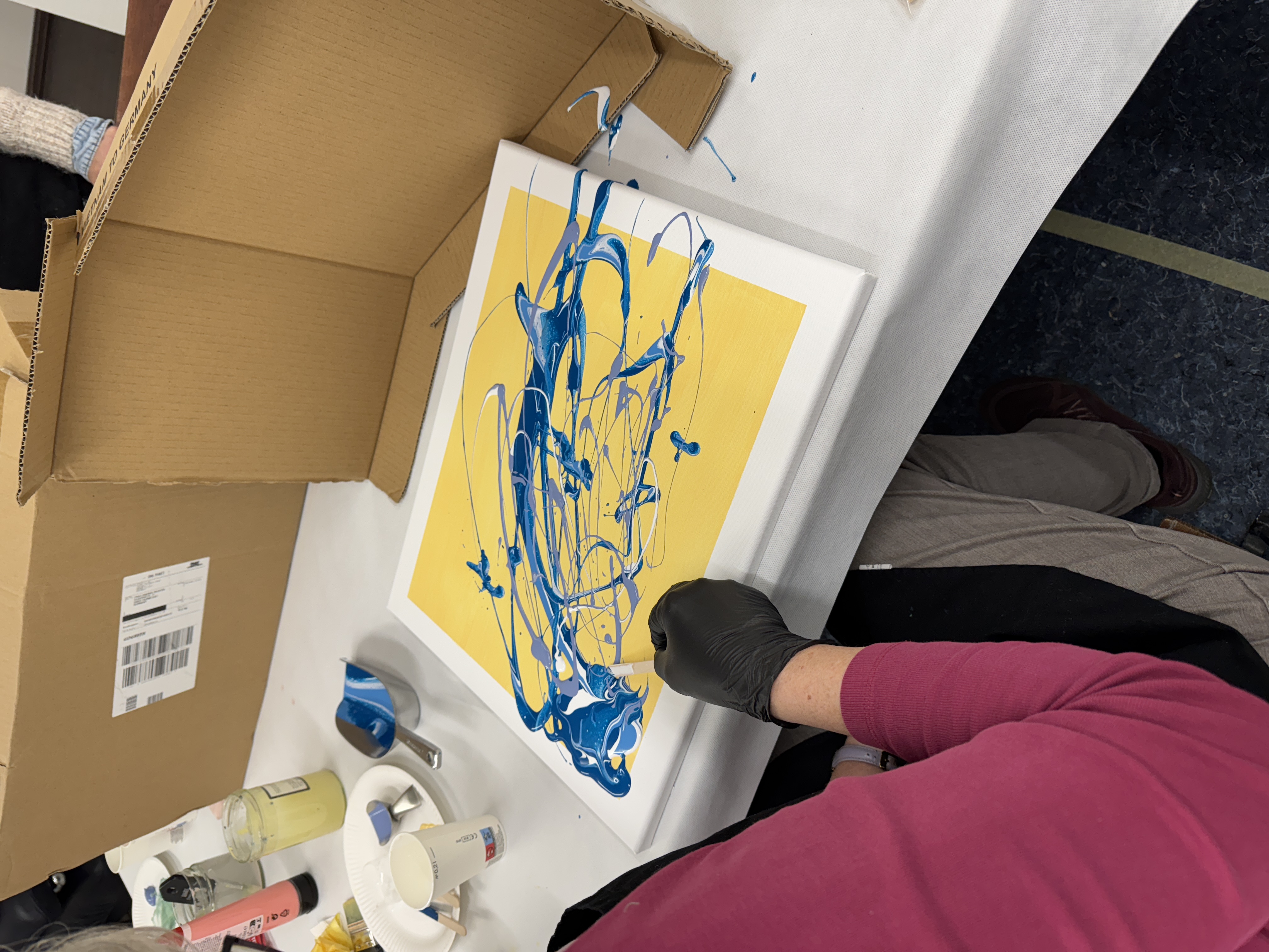 Person erstellt abstraktes blaues Gemälde auf Leinwand.