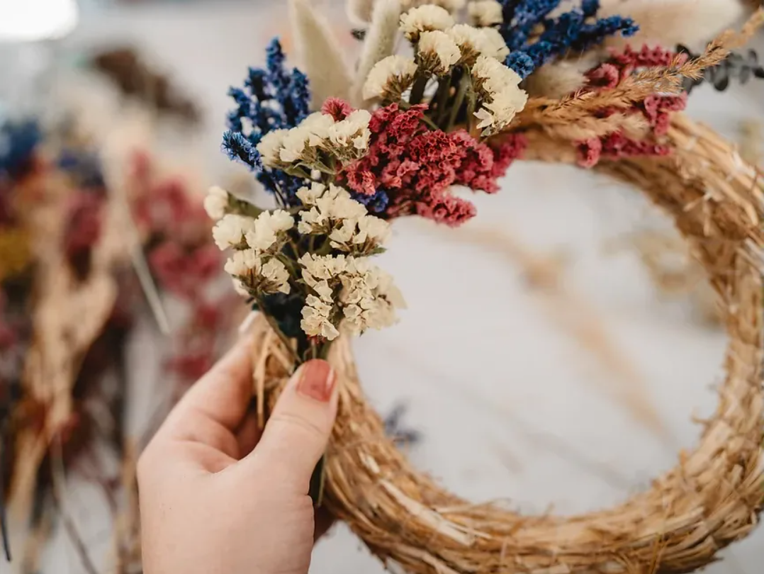 Hand holding colorful dried flower wreath.
