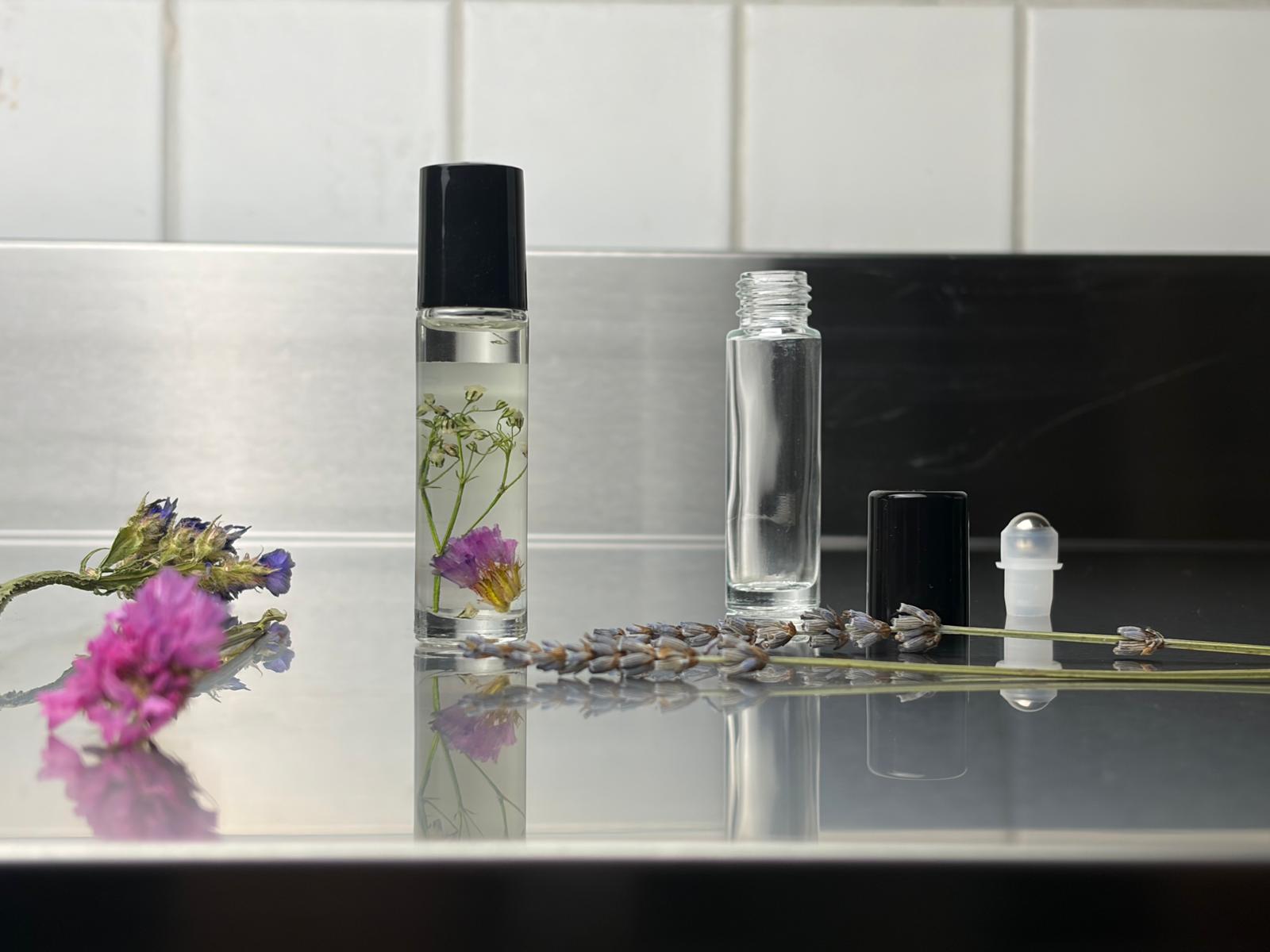 Glass bottles with flowers on reflective surface.