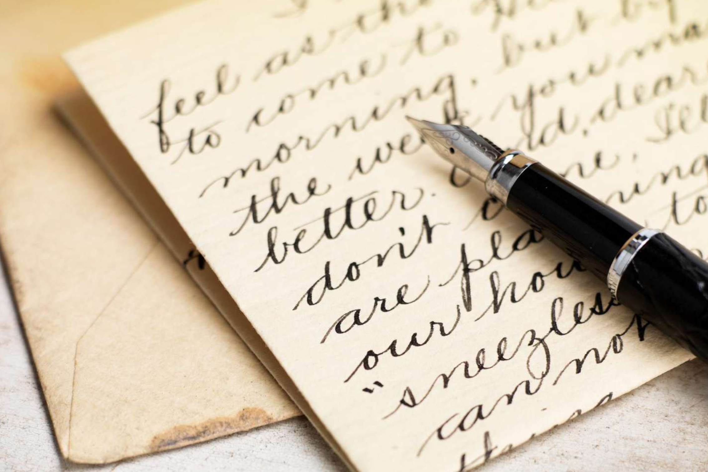 Fountain pen on handwritten letter, envelopes nearby.