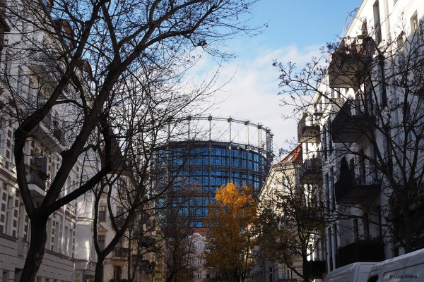 Gasometer surrounded by buildings and trees.