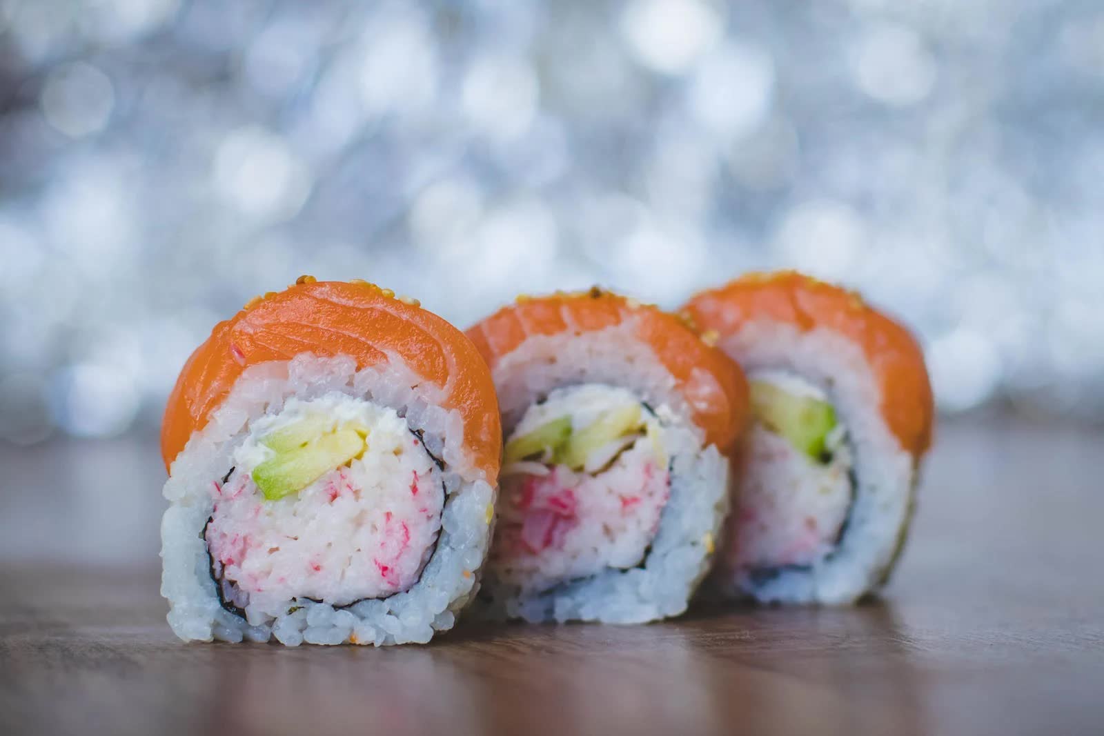 Sushirollen liegen auf einem Tisch mit unscharfem Hintergrund.