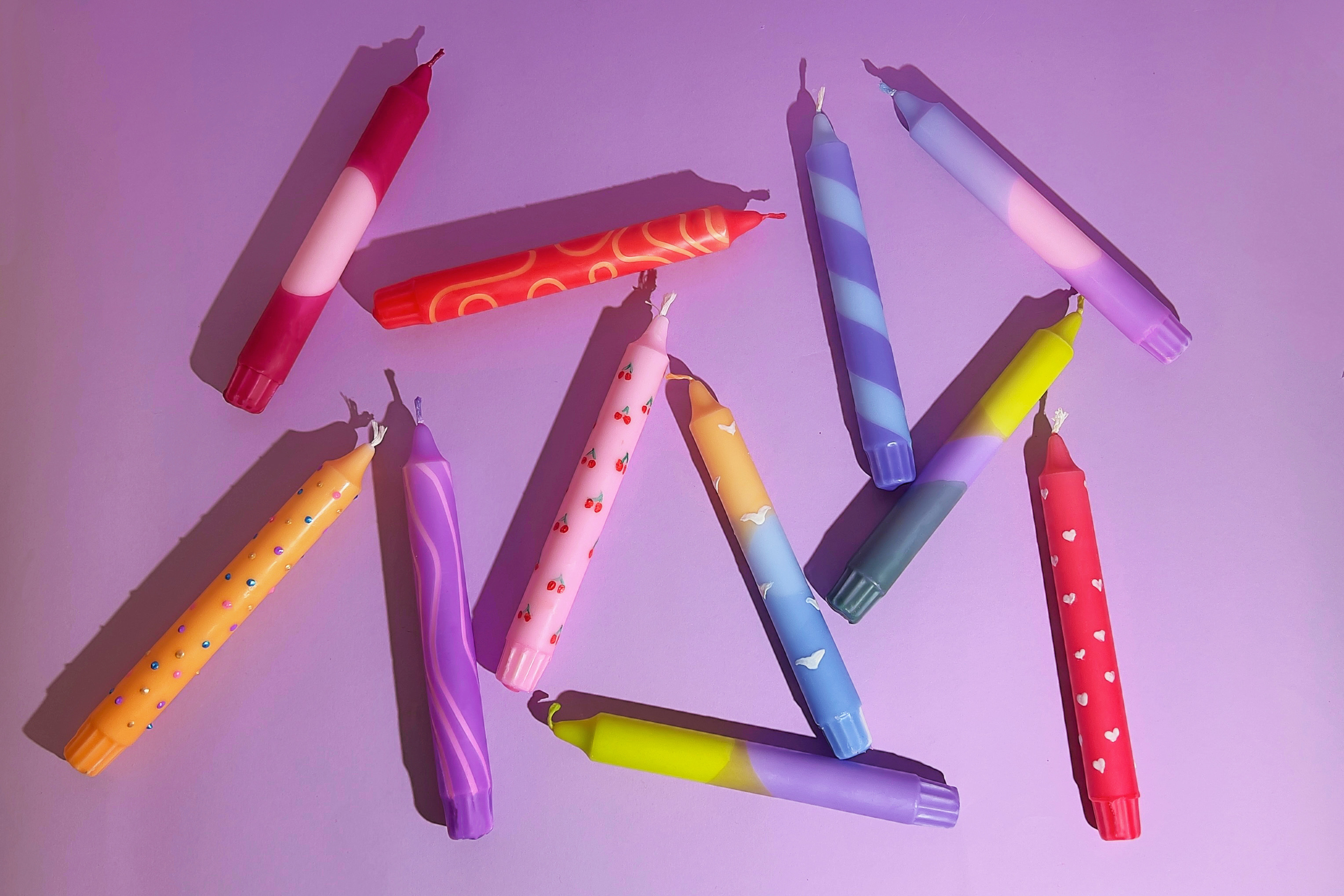 Colorful patterned candles on a purple background.