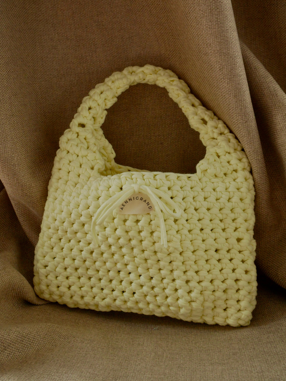 Yellow crochet bag with label on fabric.