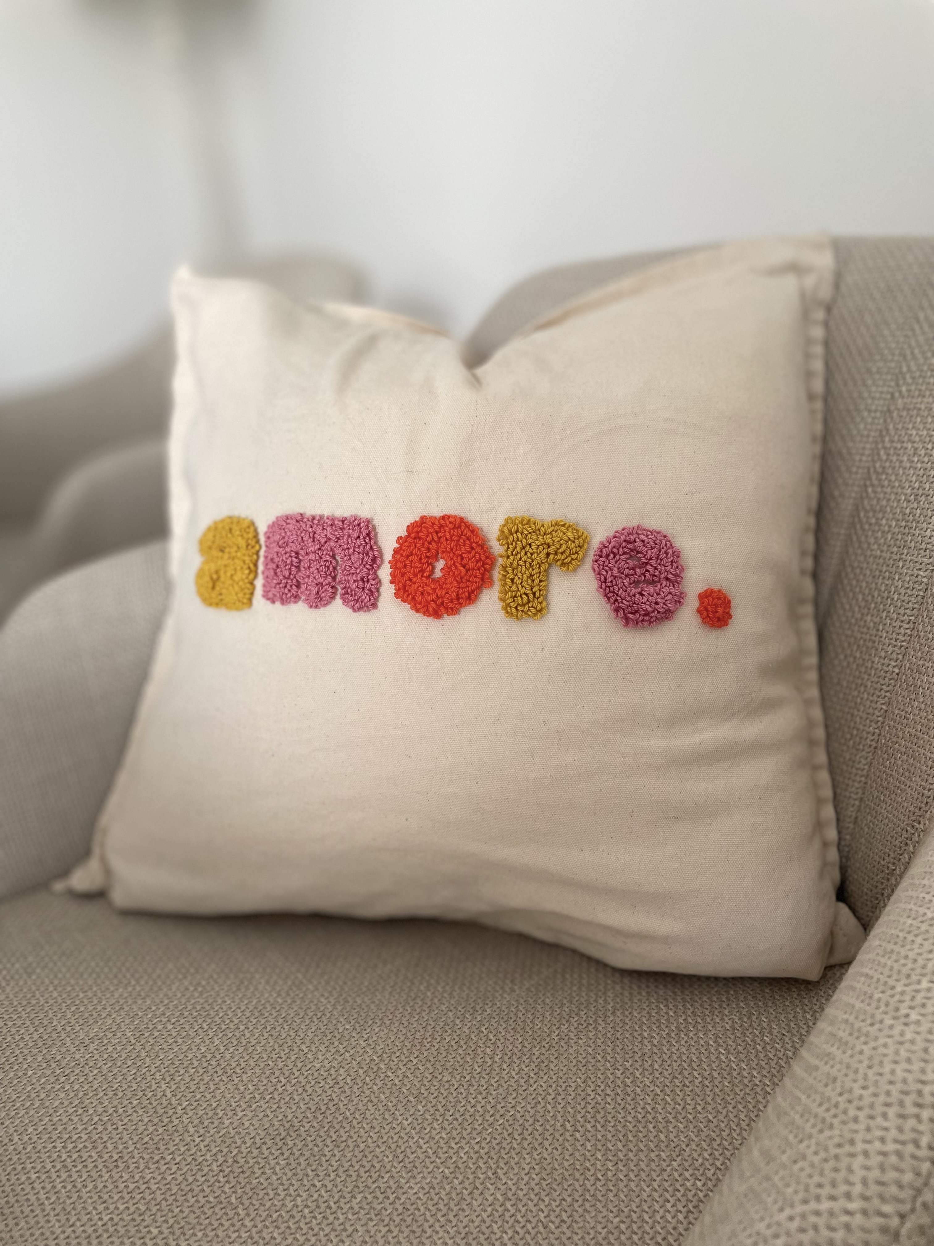 Pillow with 'amore.' text on sofa.