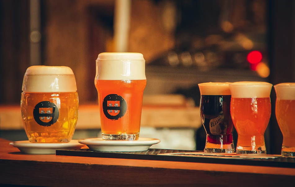 Fünf Biere mit Schaum auf einer Holzbar.