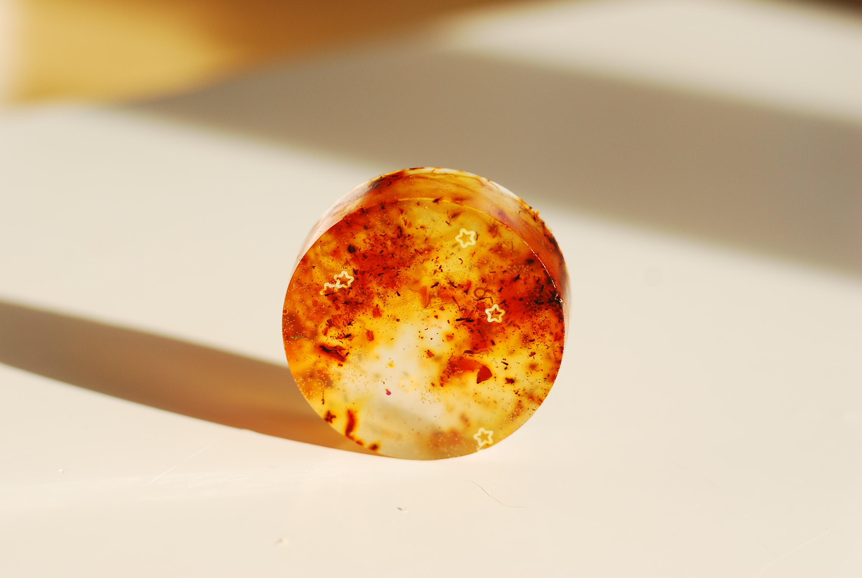 Round amber object with cloudy texture, sunlight casting.