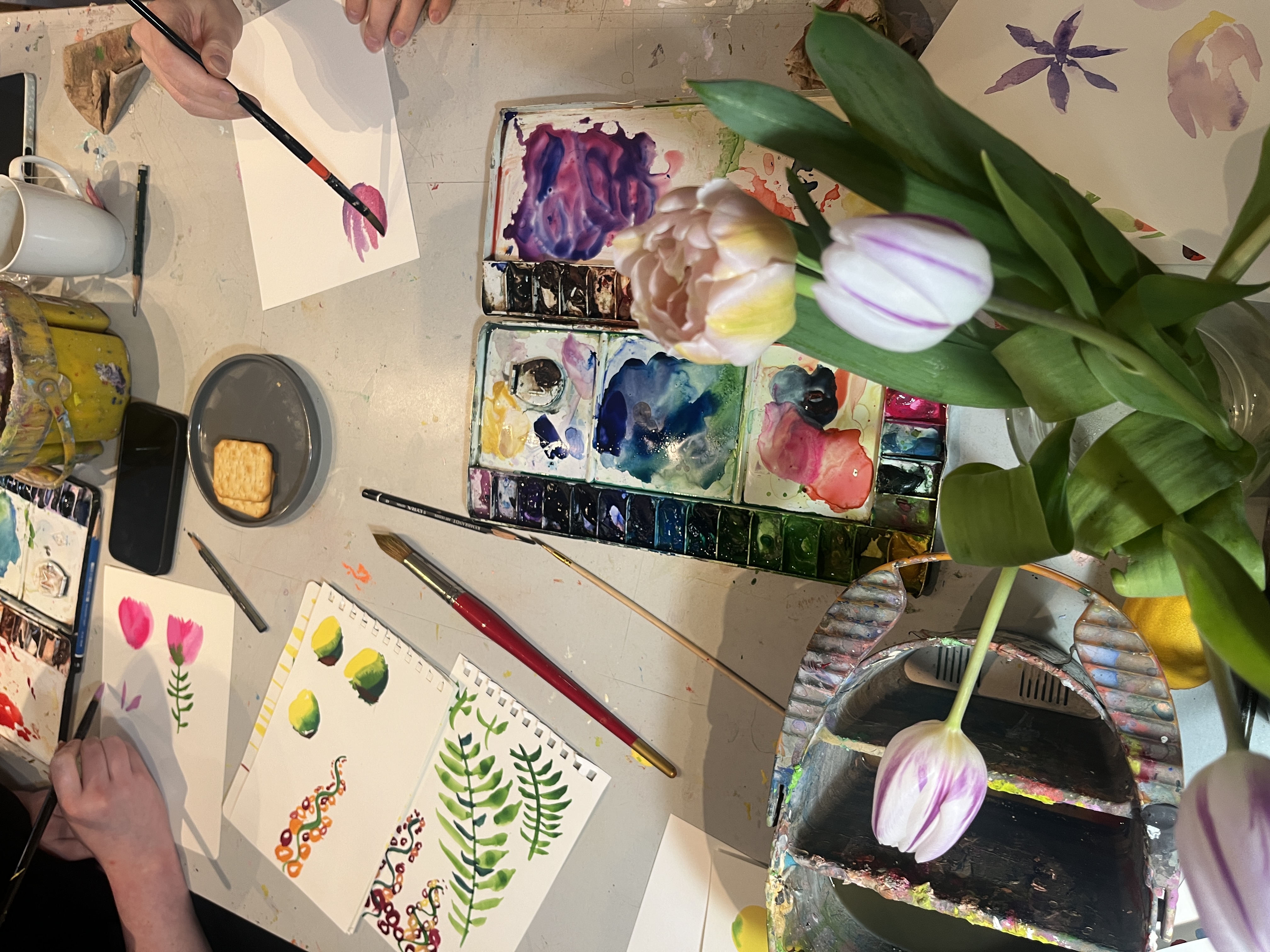 People painting flowers at a table.