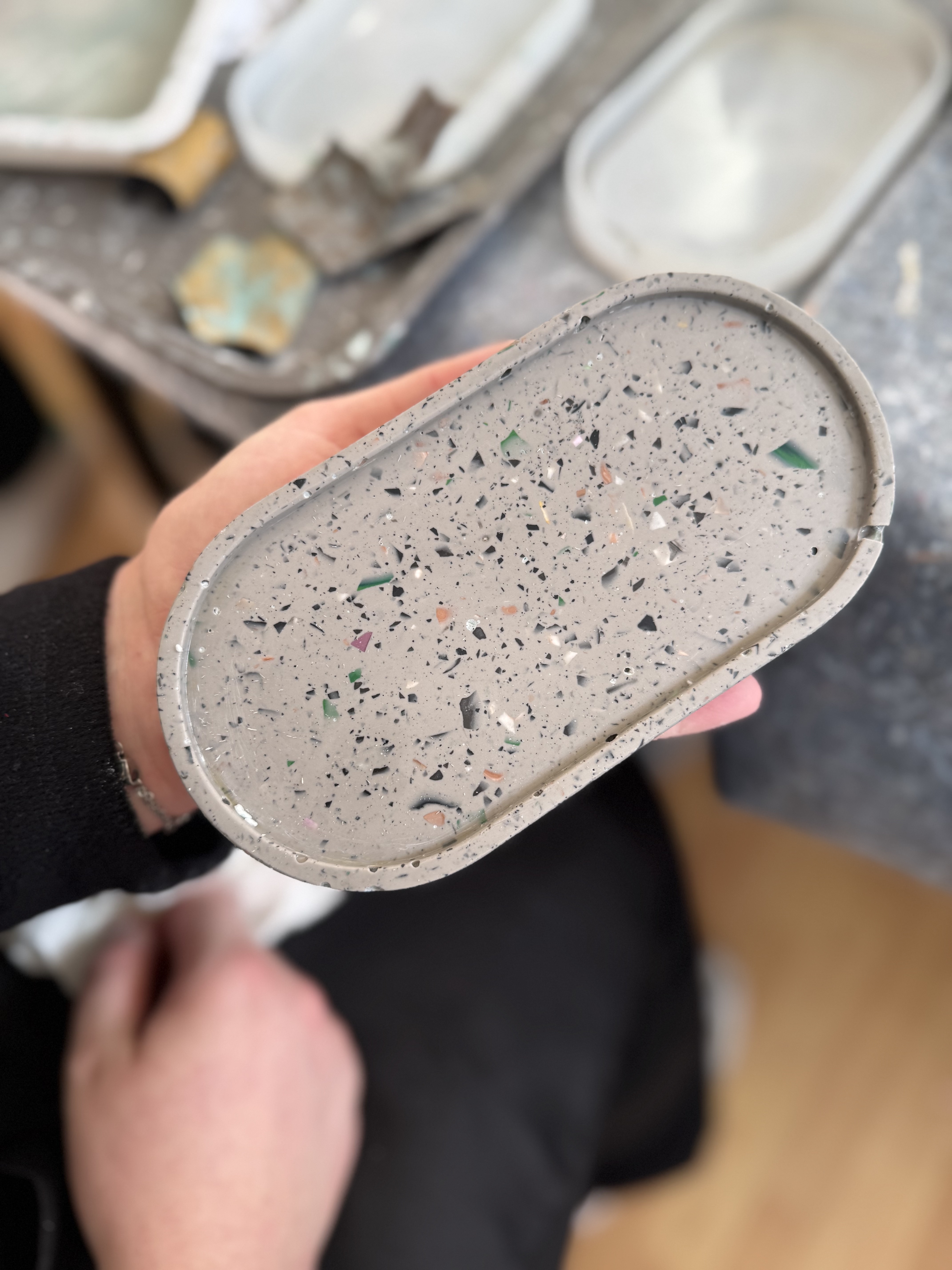 Hand hält gesprenkeltes ovales Tablett innen.
