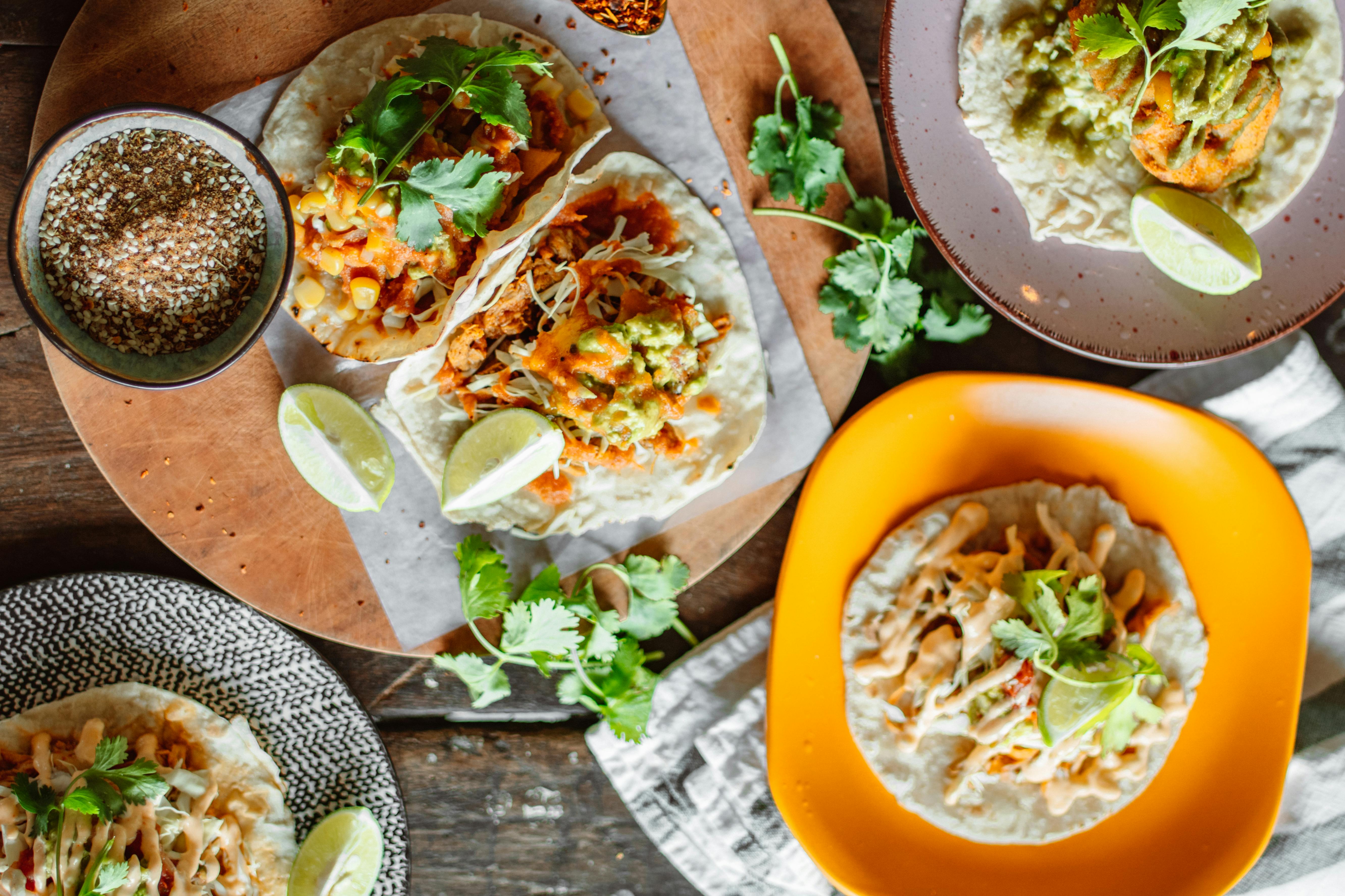 Tacos with toppings on wooden table.