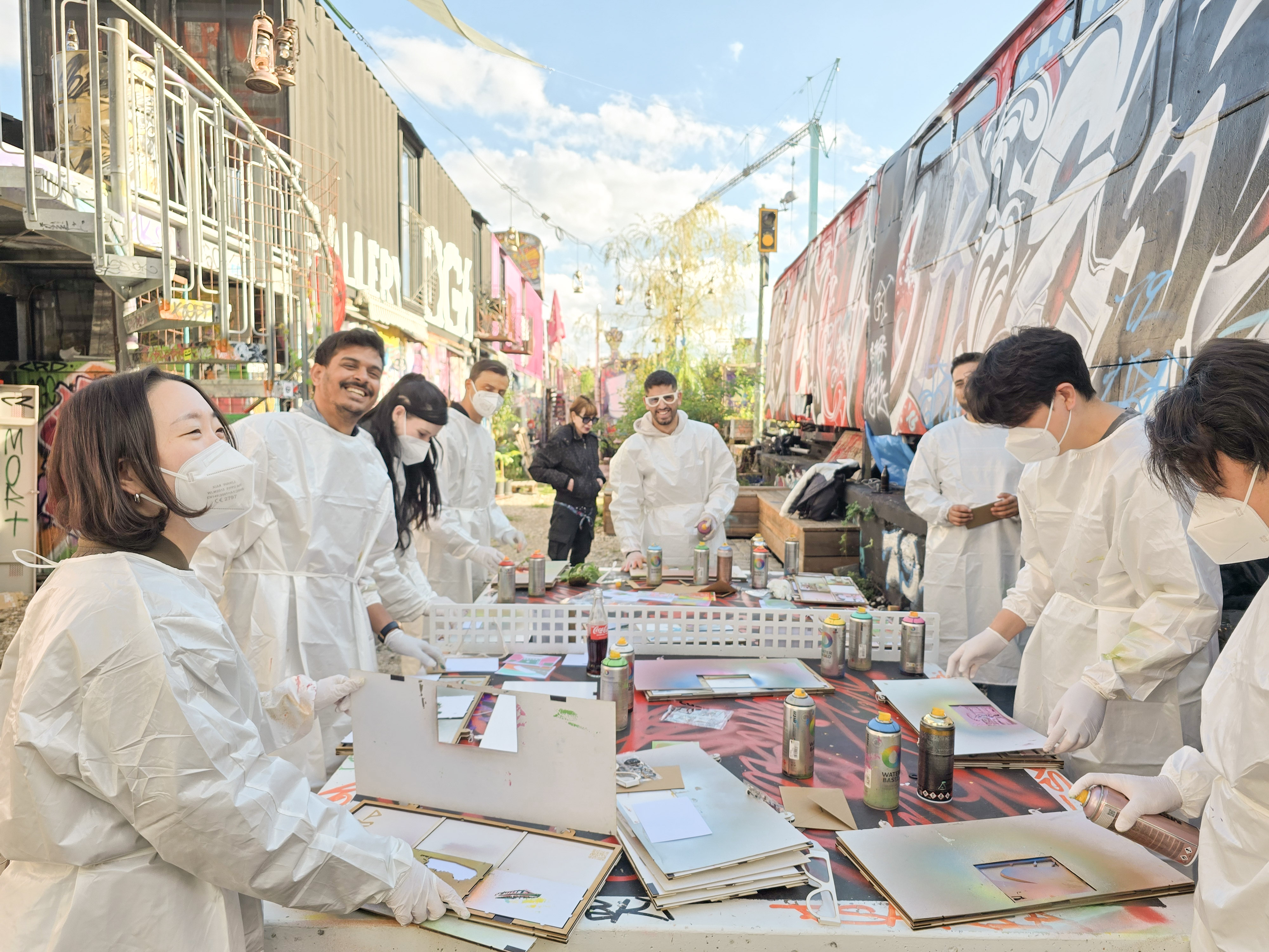 People in protective suits painting with spray paint outdoors.