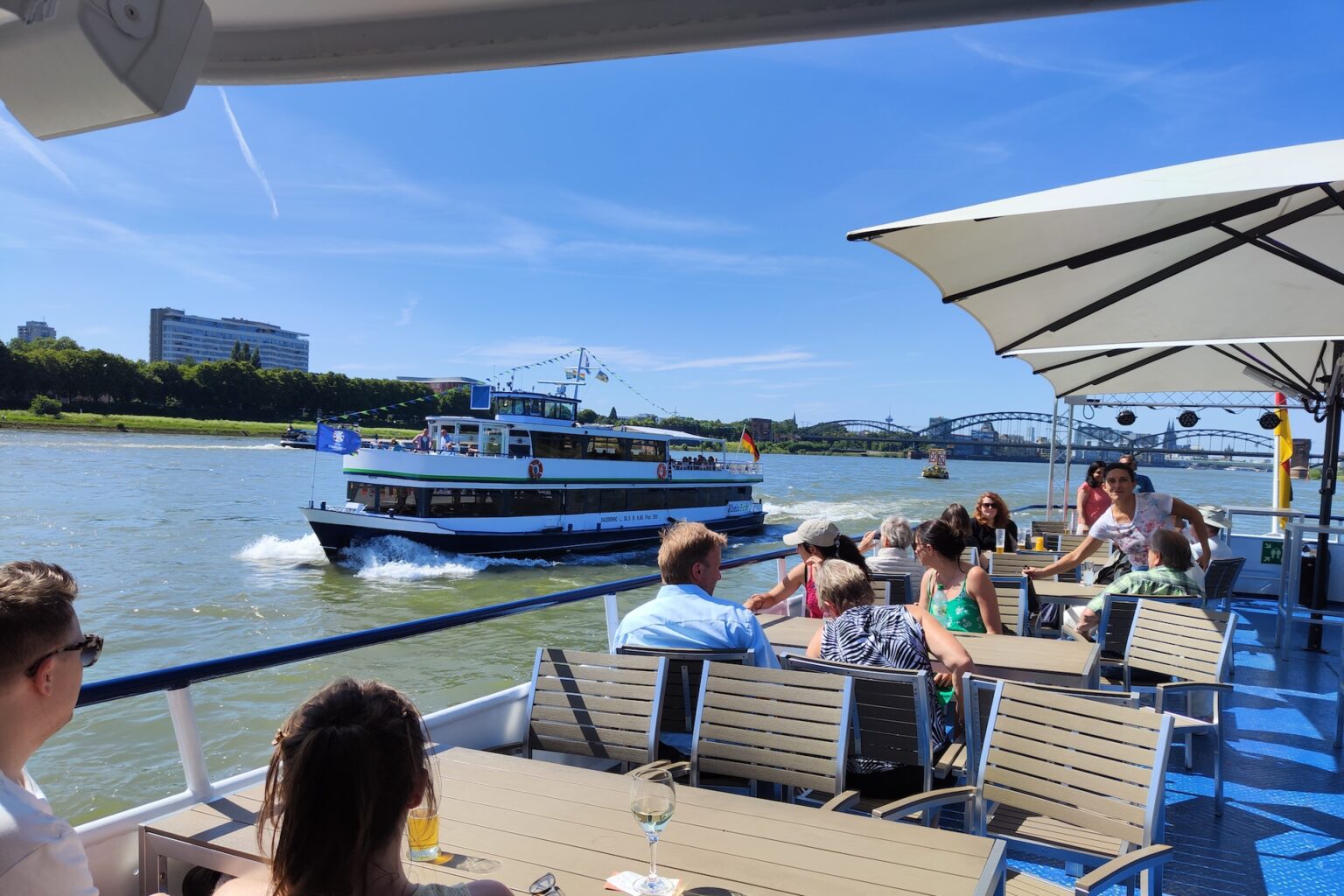People relaxing on riverboat under umbrella.