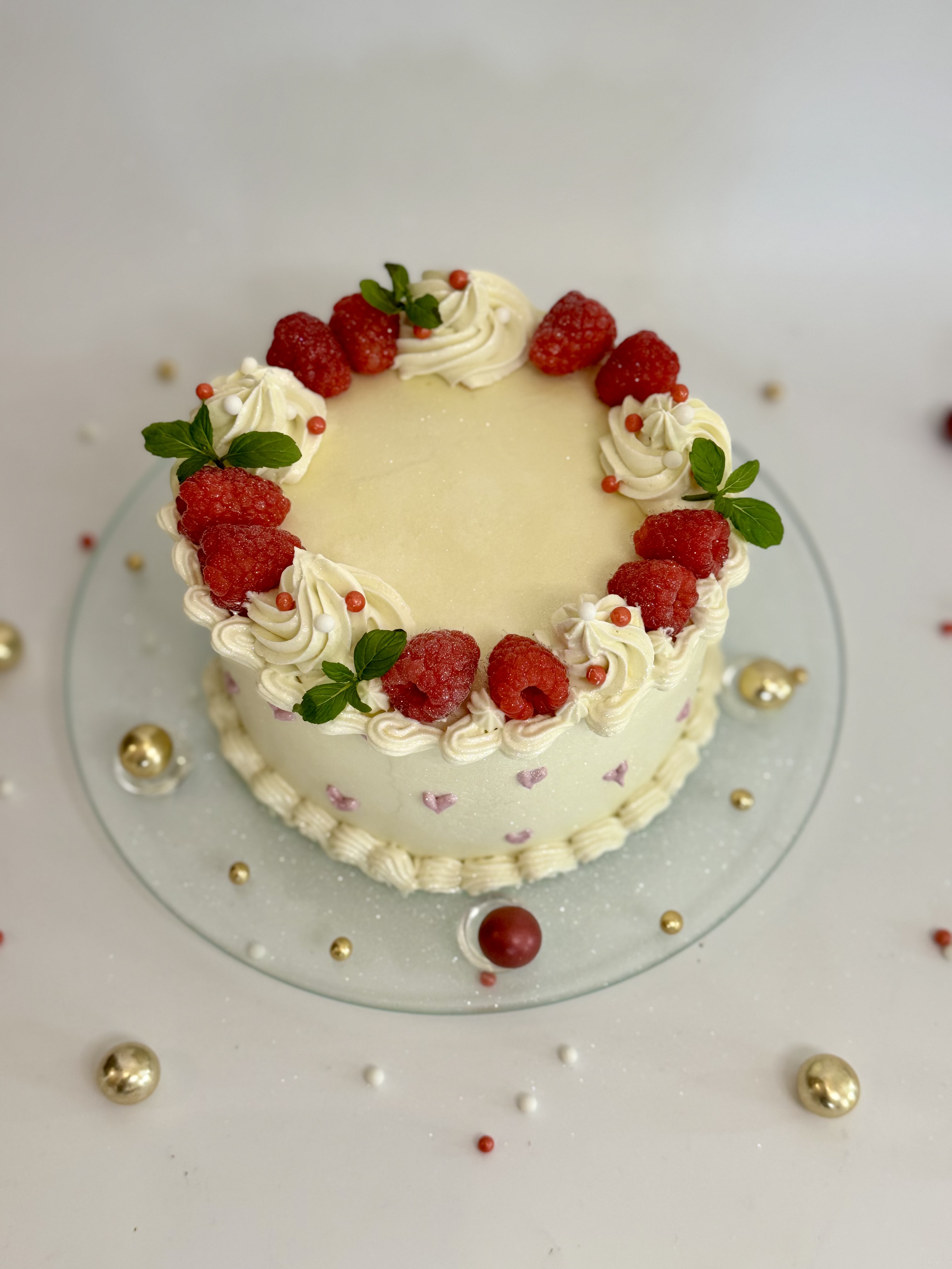 Decorated cake with raspberries on white surface.