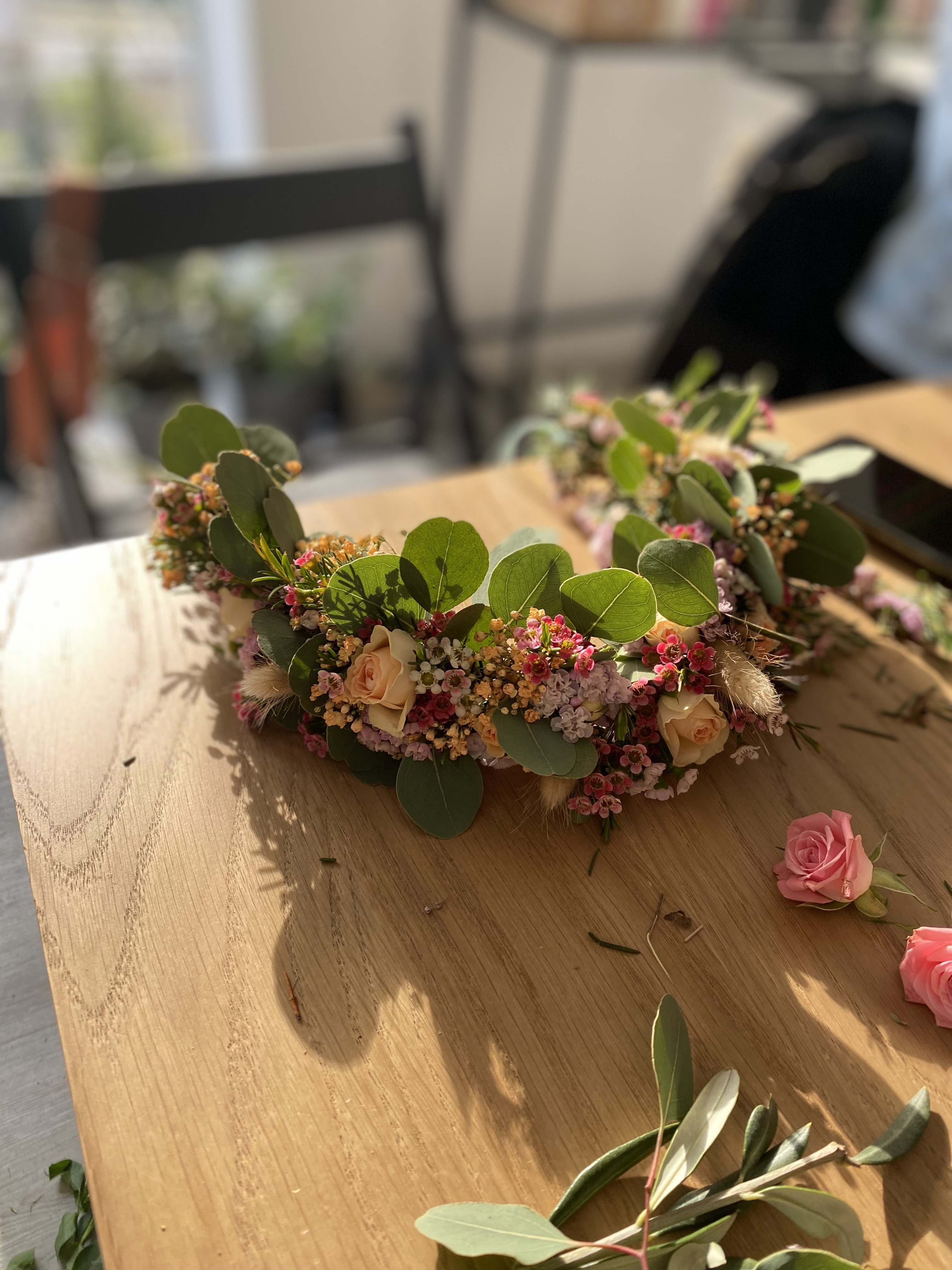Blumenkranz mit Rosen auf Holztisch.