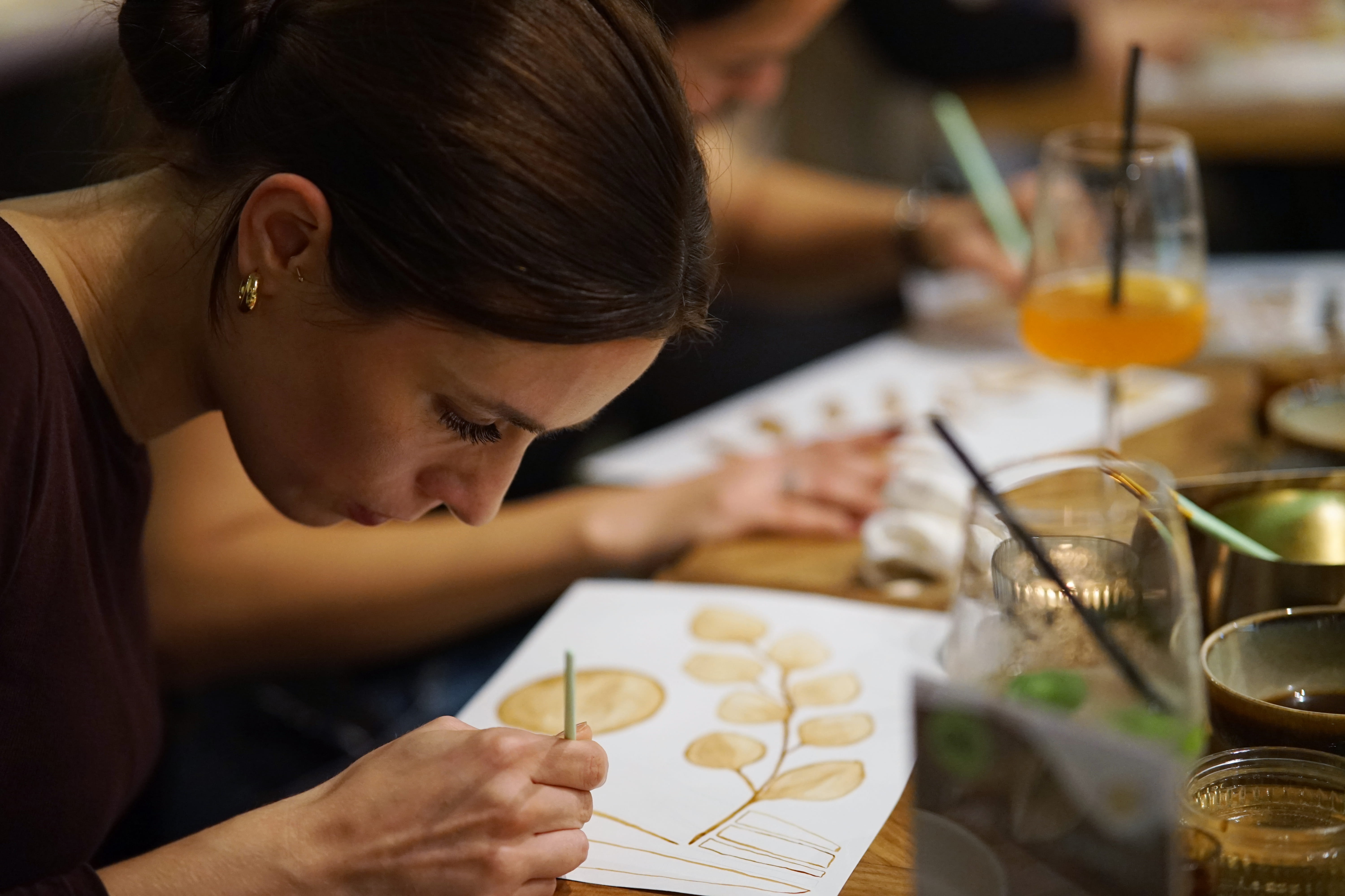 Woman painting leaves at a table.