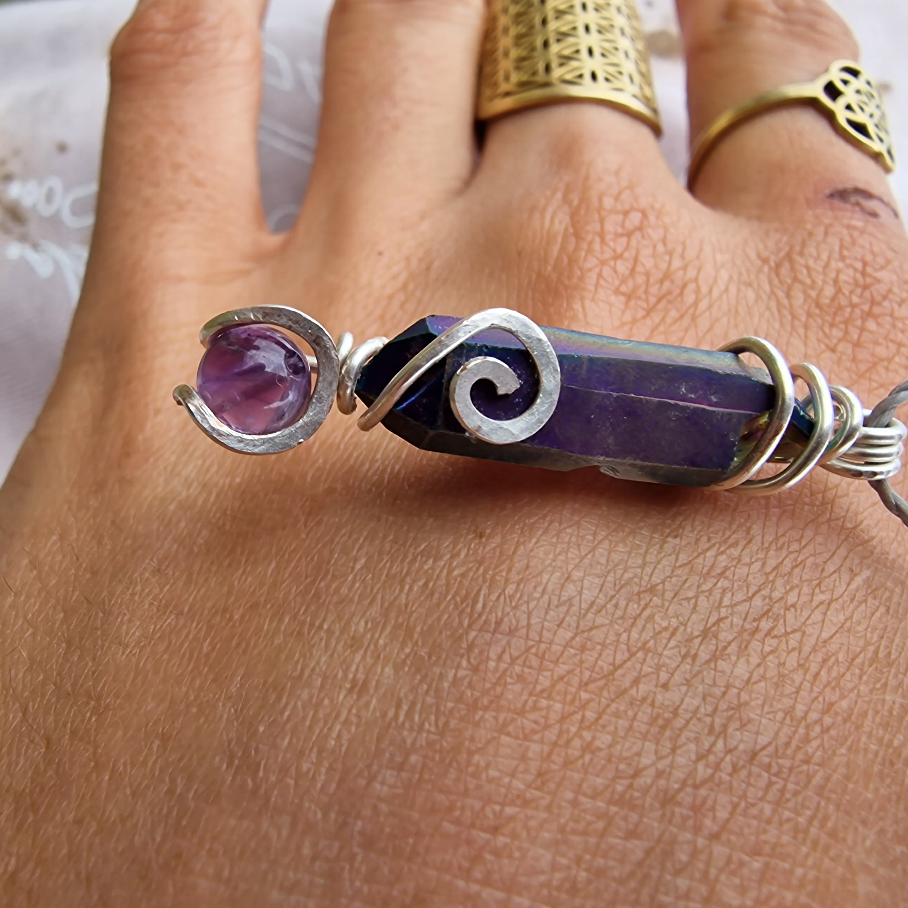 Lila Kristallanhänger auf Hand mit Ringen.
