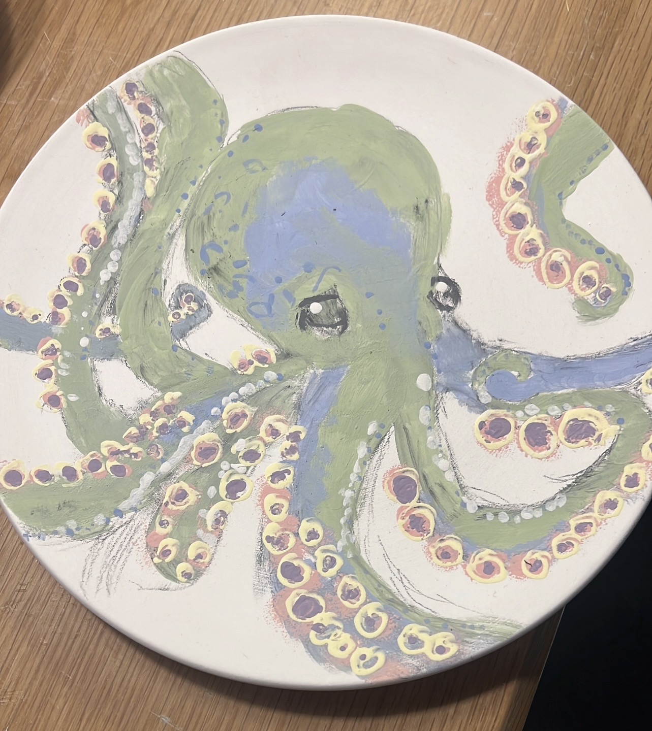 Painted octopus on ceramic plate, wooden table.