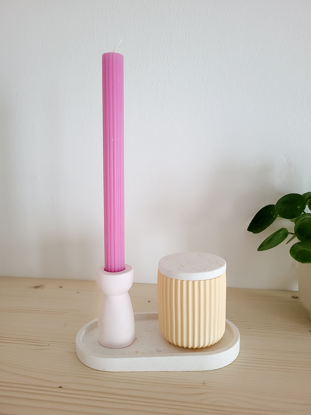 Rosa Kerze und Behälter auf Holztablett.