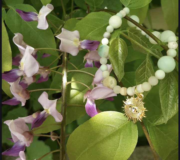 Bracelet and flowers among lush green leaves.