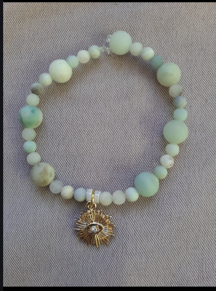 Beaded bracelet with sun-eye pendant on fabric.