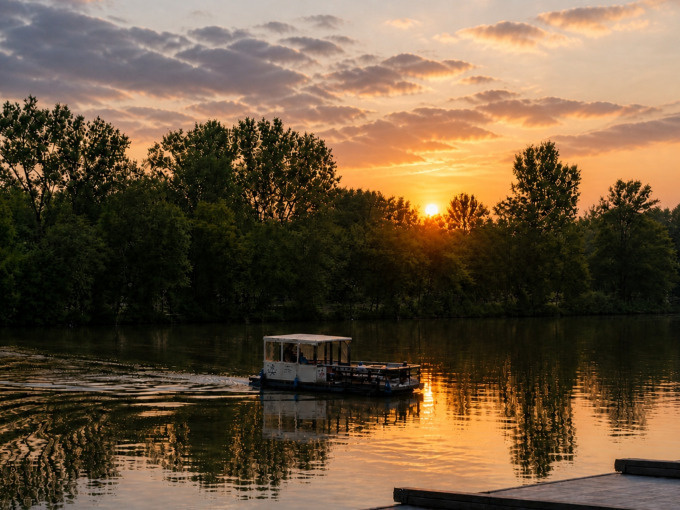 Boot fährt bei Sonnenuntergang auf einem See.