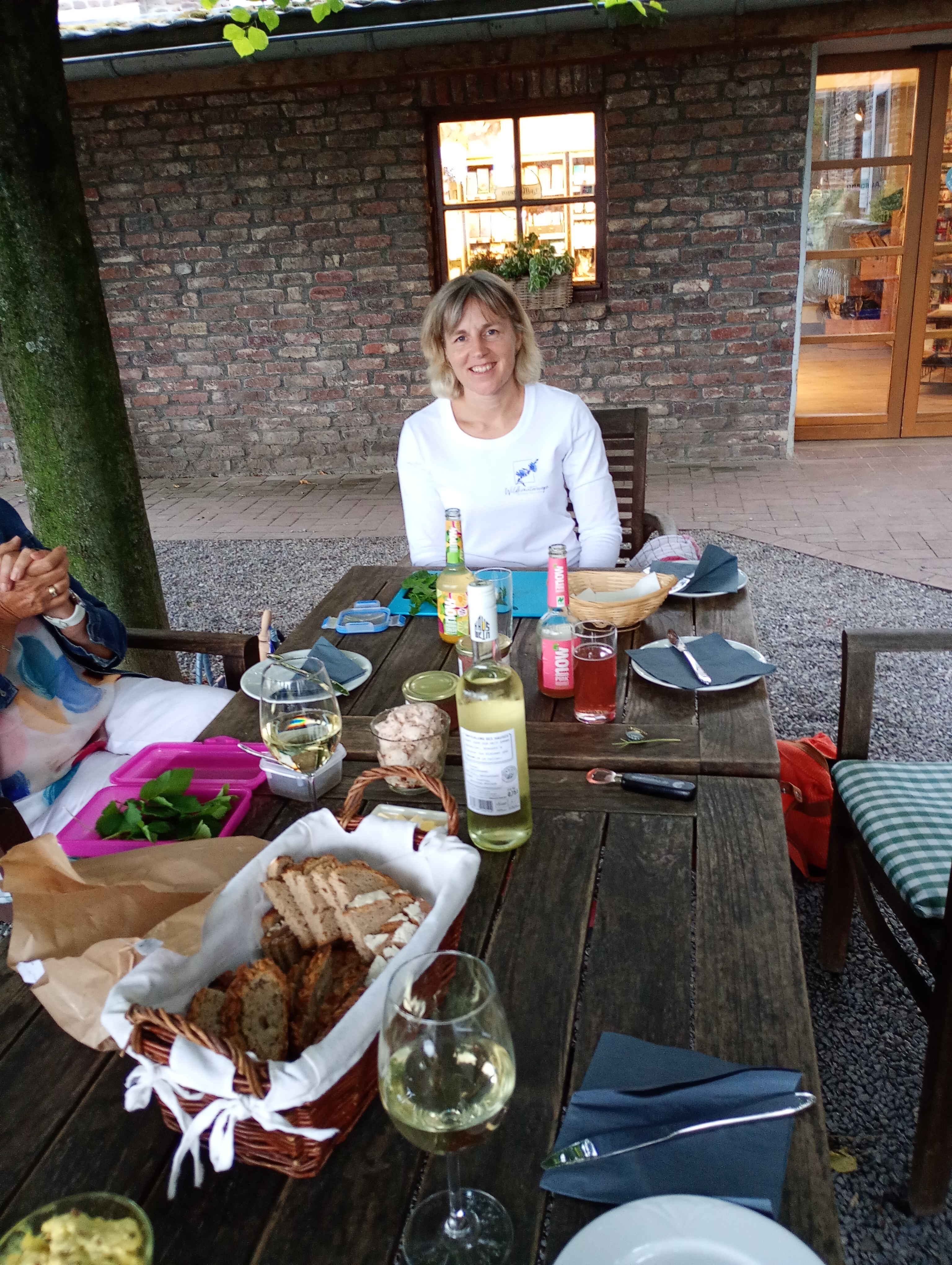 Frau sitzt draußen an einem Tisch mit Getränken.