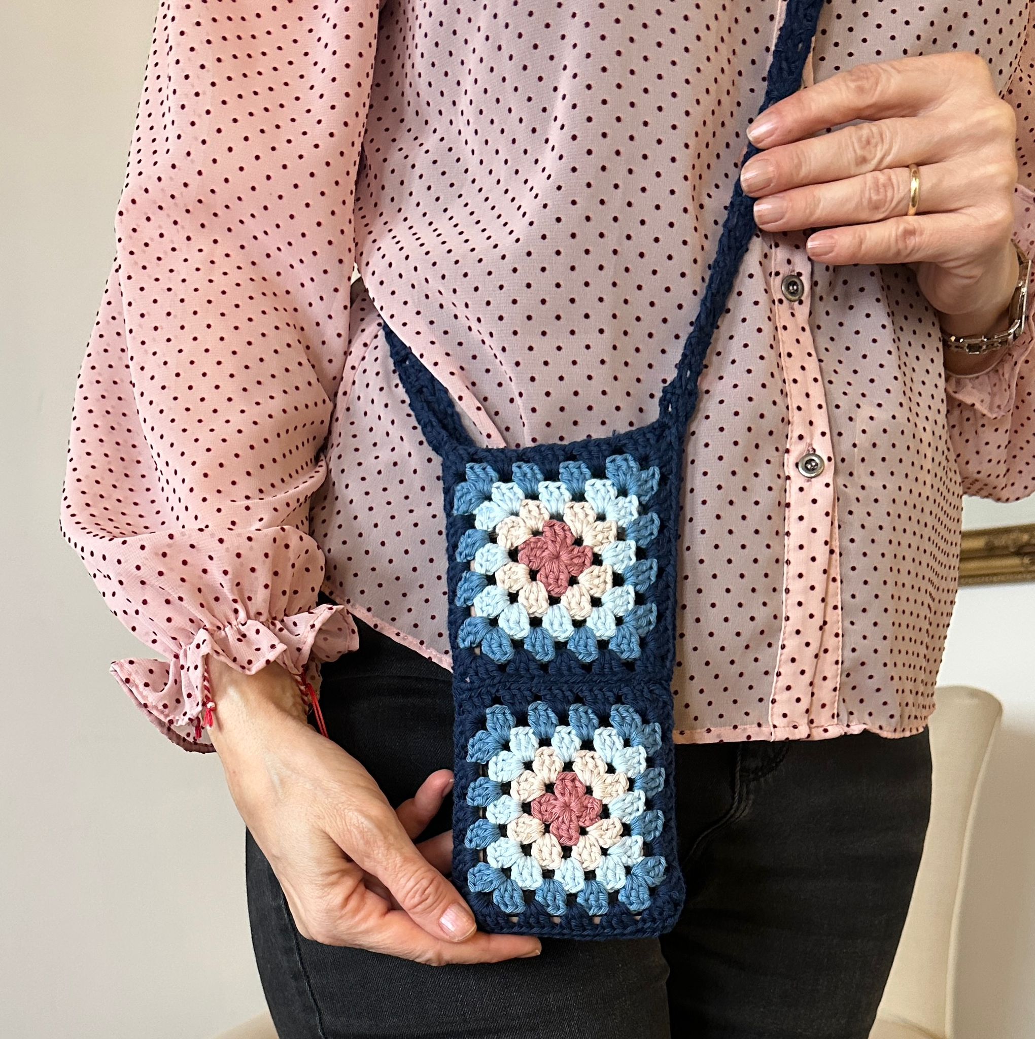 Crochet bag held by woman in pink blouse.