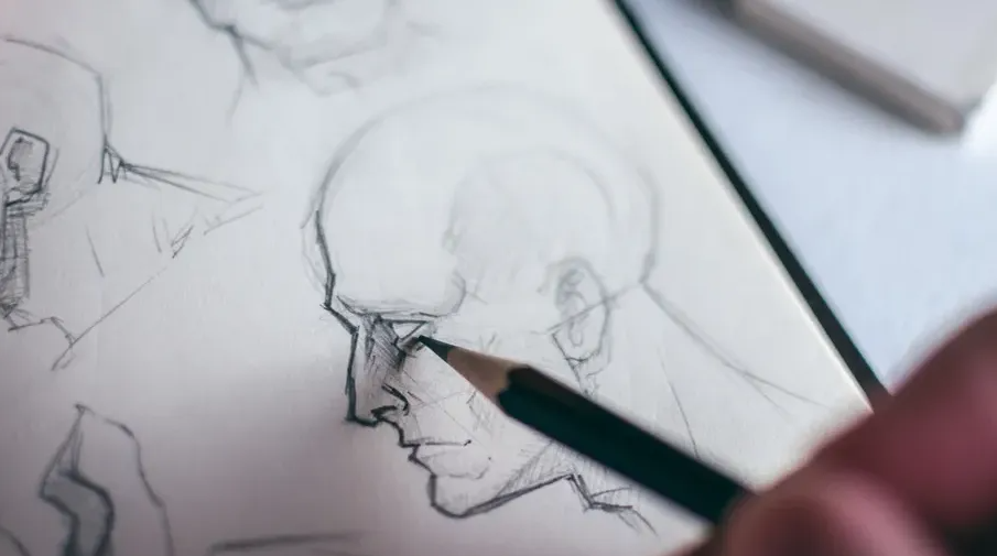 Person drawing a face on sketchbook.