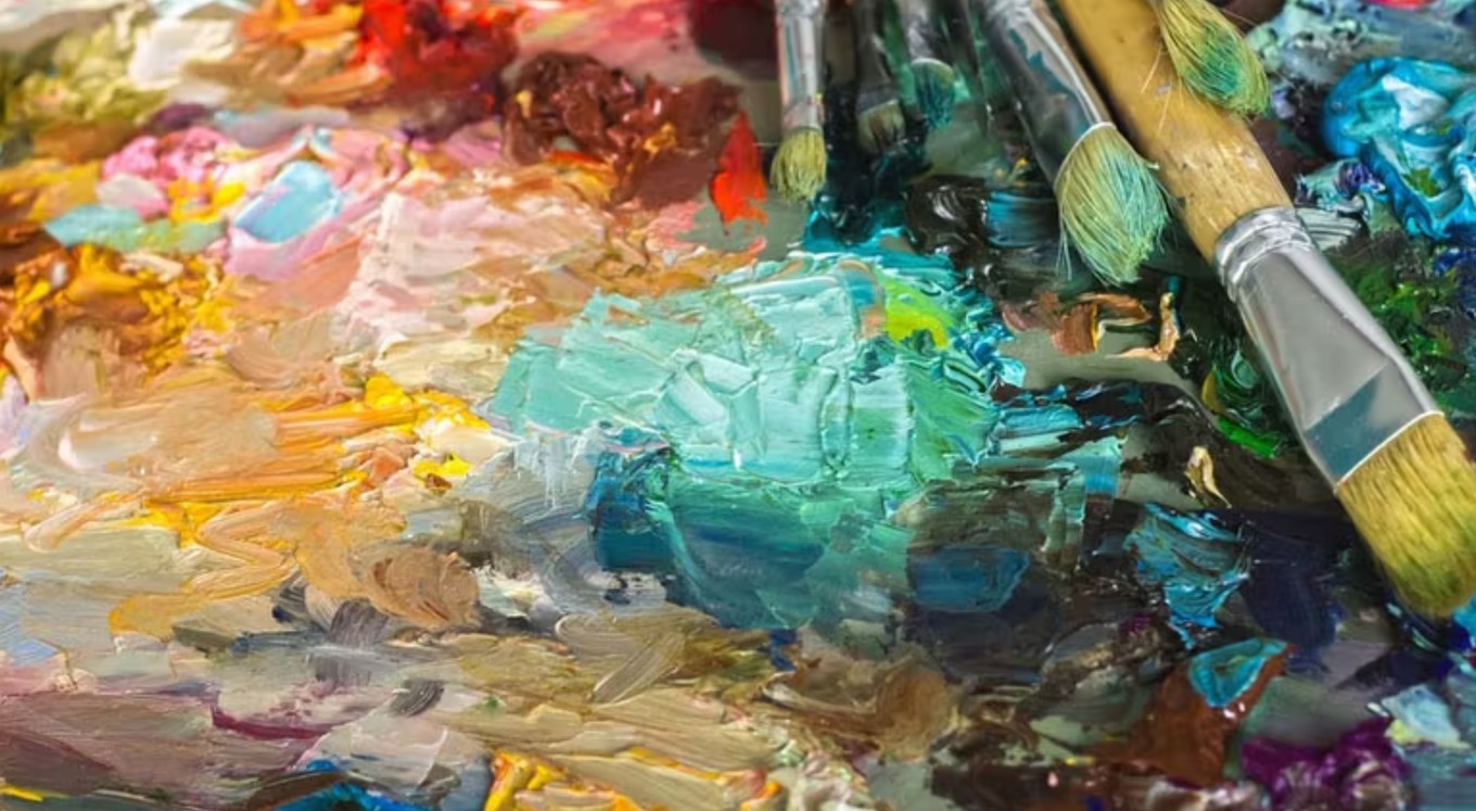 Paintbrushes rest on colorful paint palette.