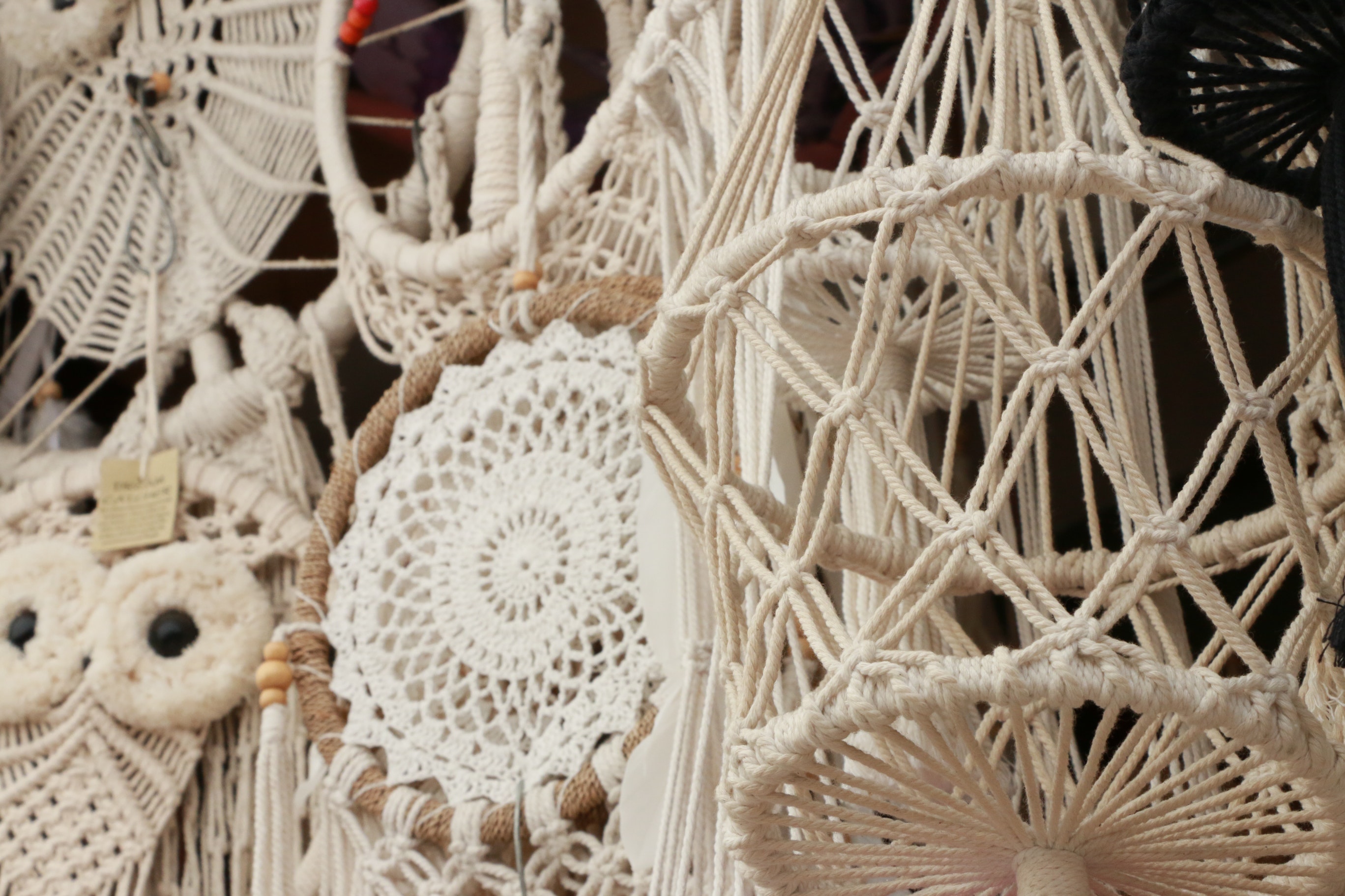 Handmade macrame decorations hang in a market.