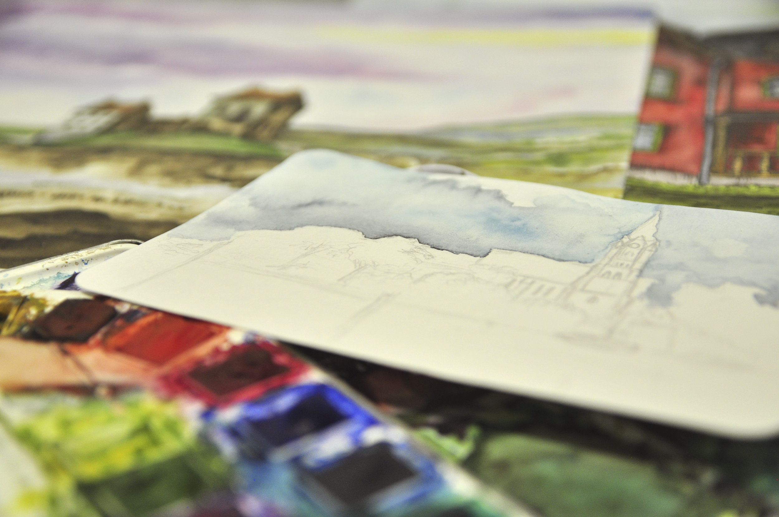 Watercolor sketches on a table with paint palette.