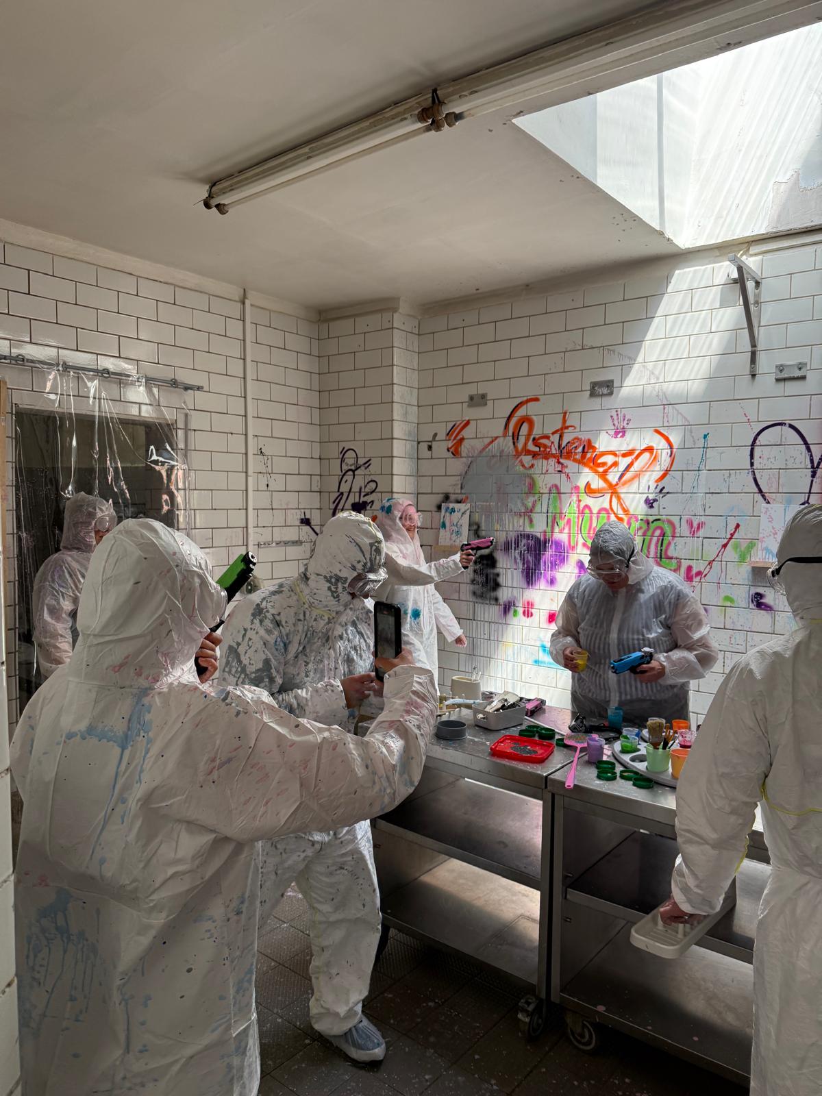 Menschen in Schutzanzügen malen Graffiti drinnen.