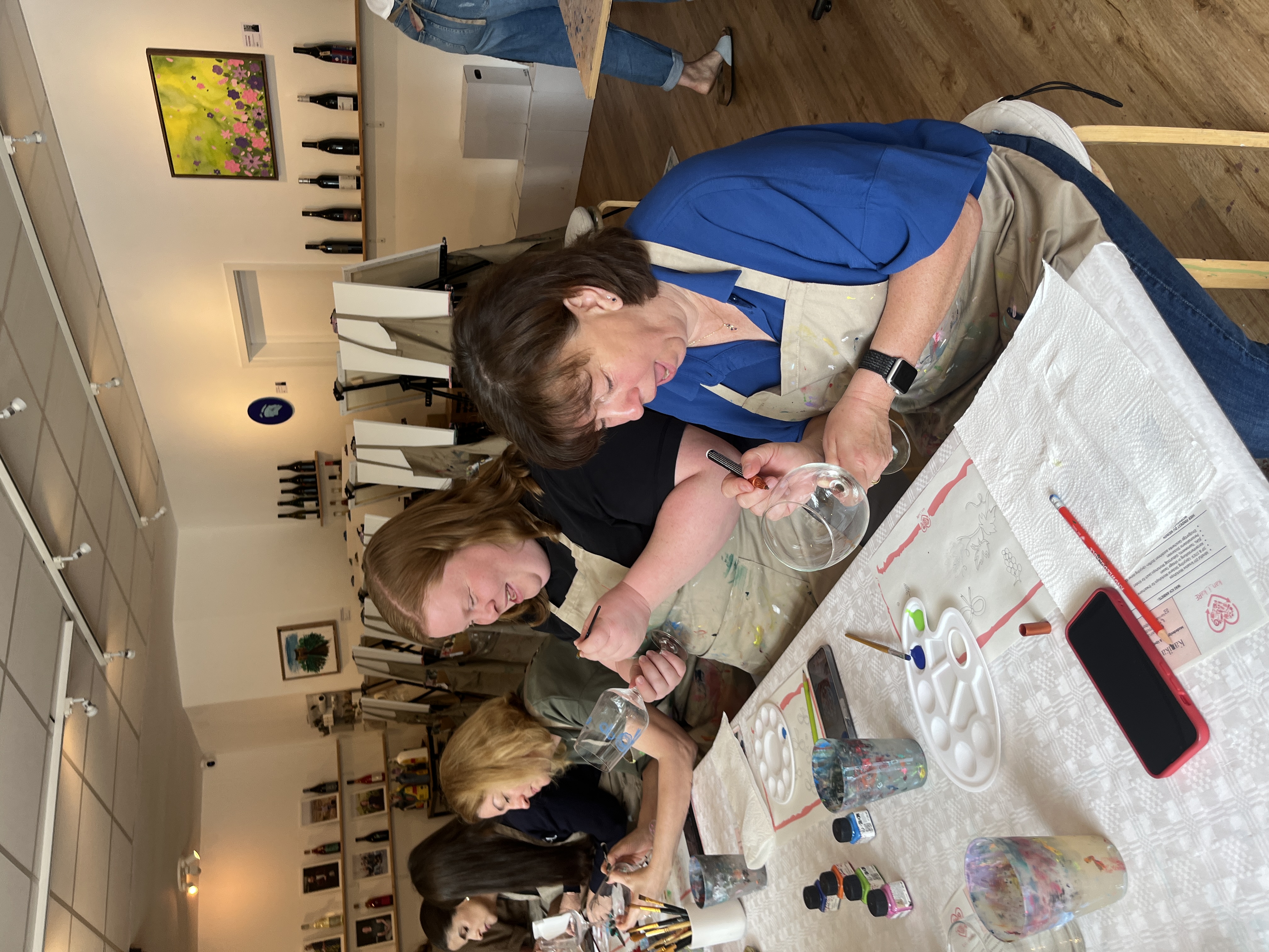 Women painting glasses in an art class.