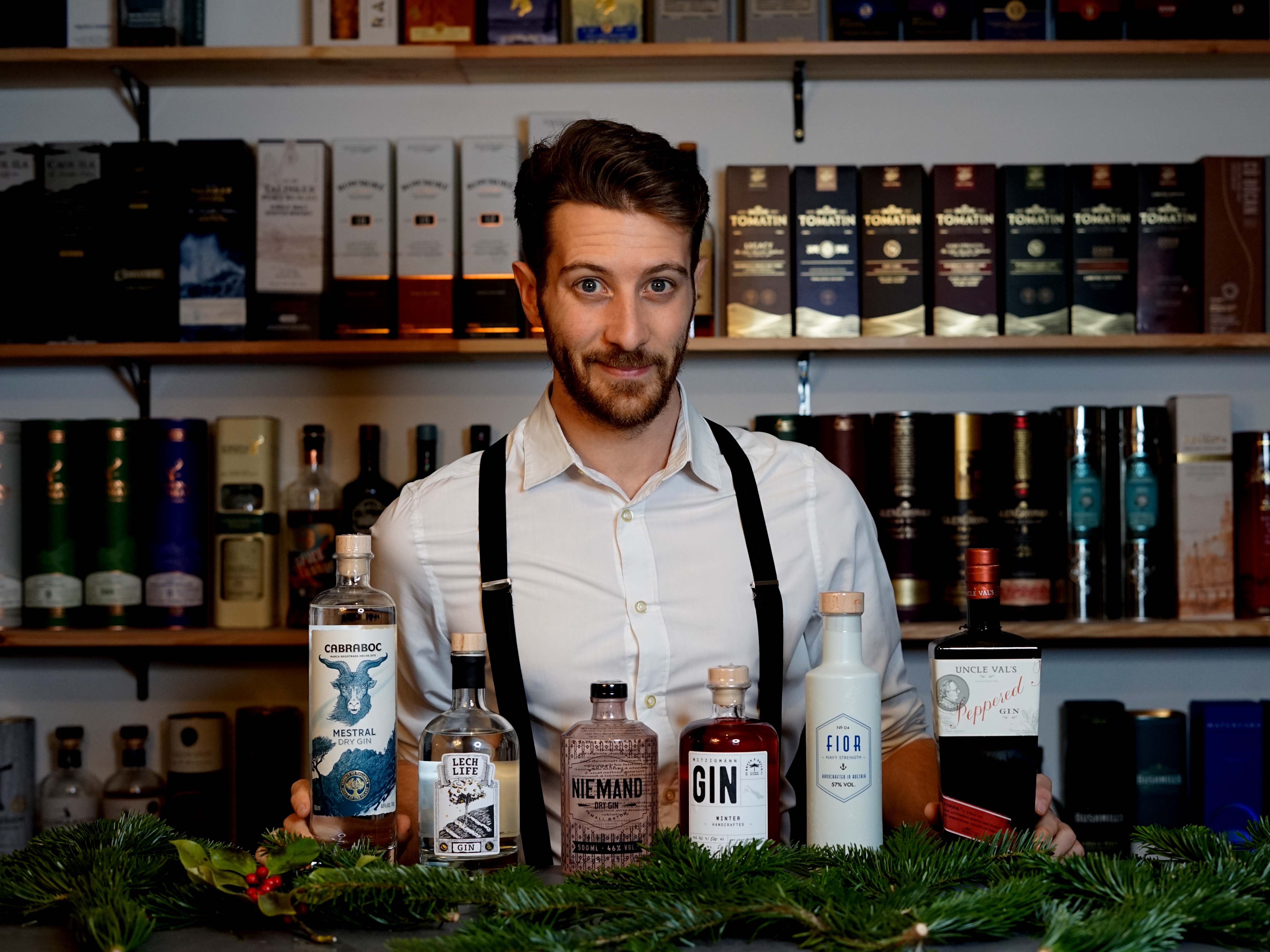 Bartender steht vor einer Bar mit verschiedenen Flaschen.