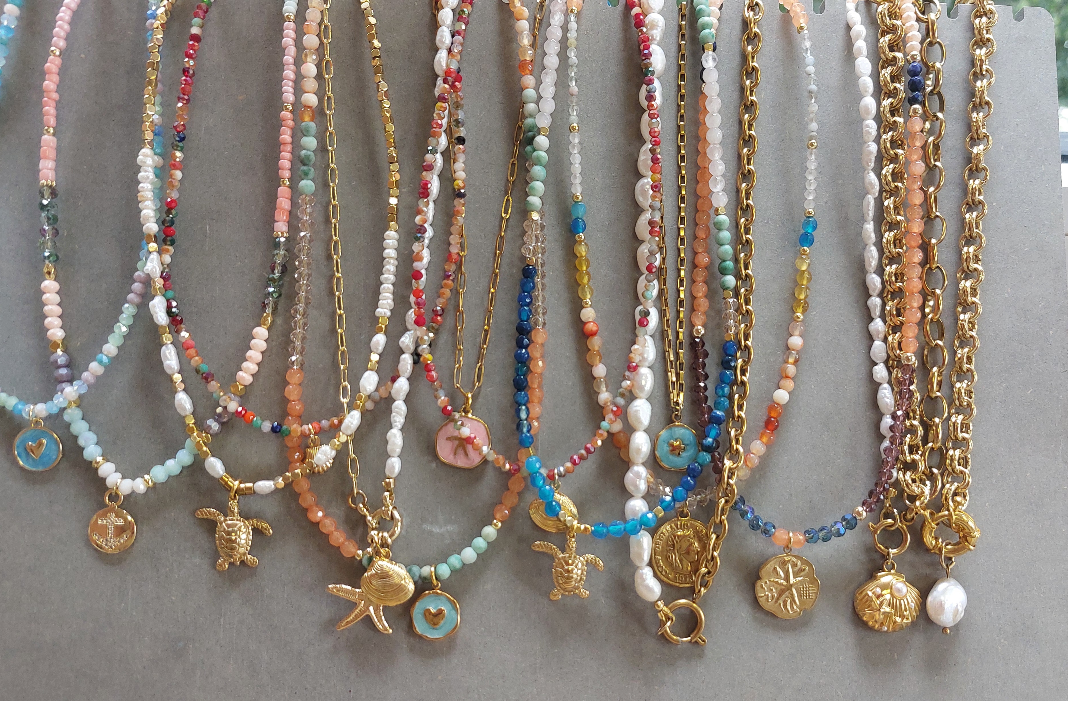 Colorful beaded necklaces with gold charms displayed.