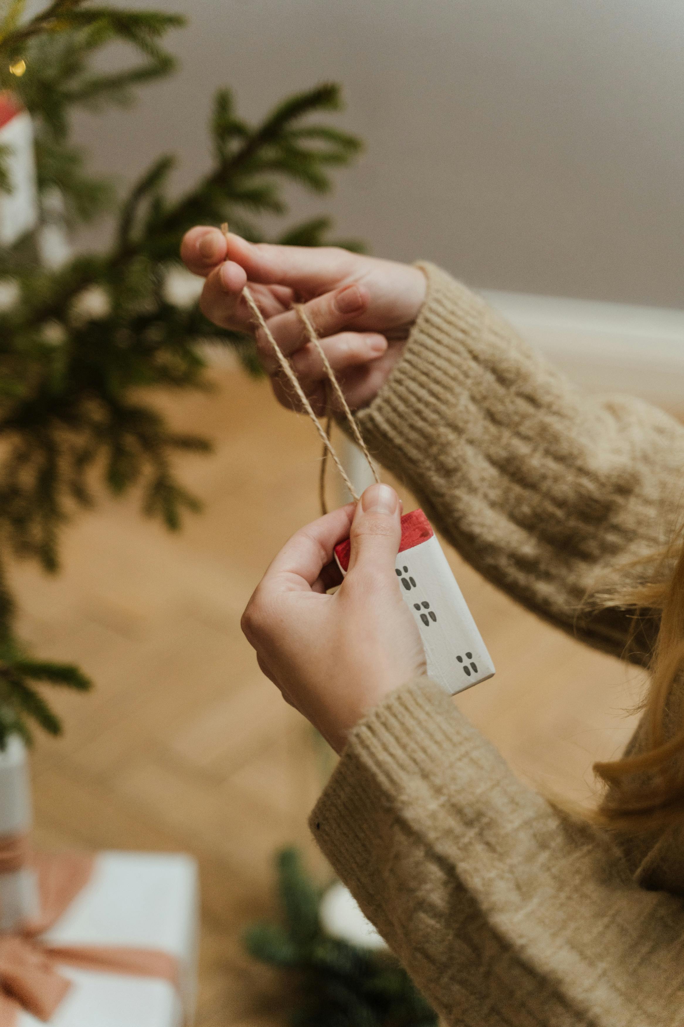 Person hält Schnur, richtet Weihnachtsornament aus.