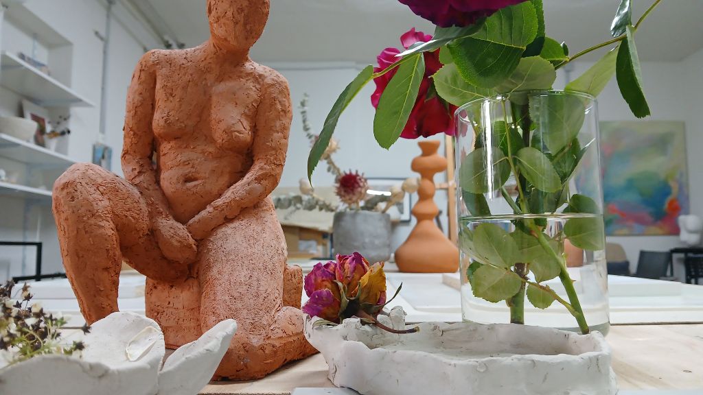Terrakottaskulptur und Blumen auf einem Tisch.