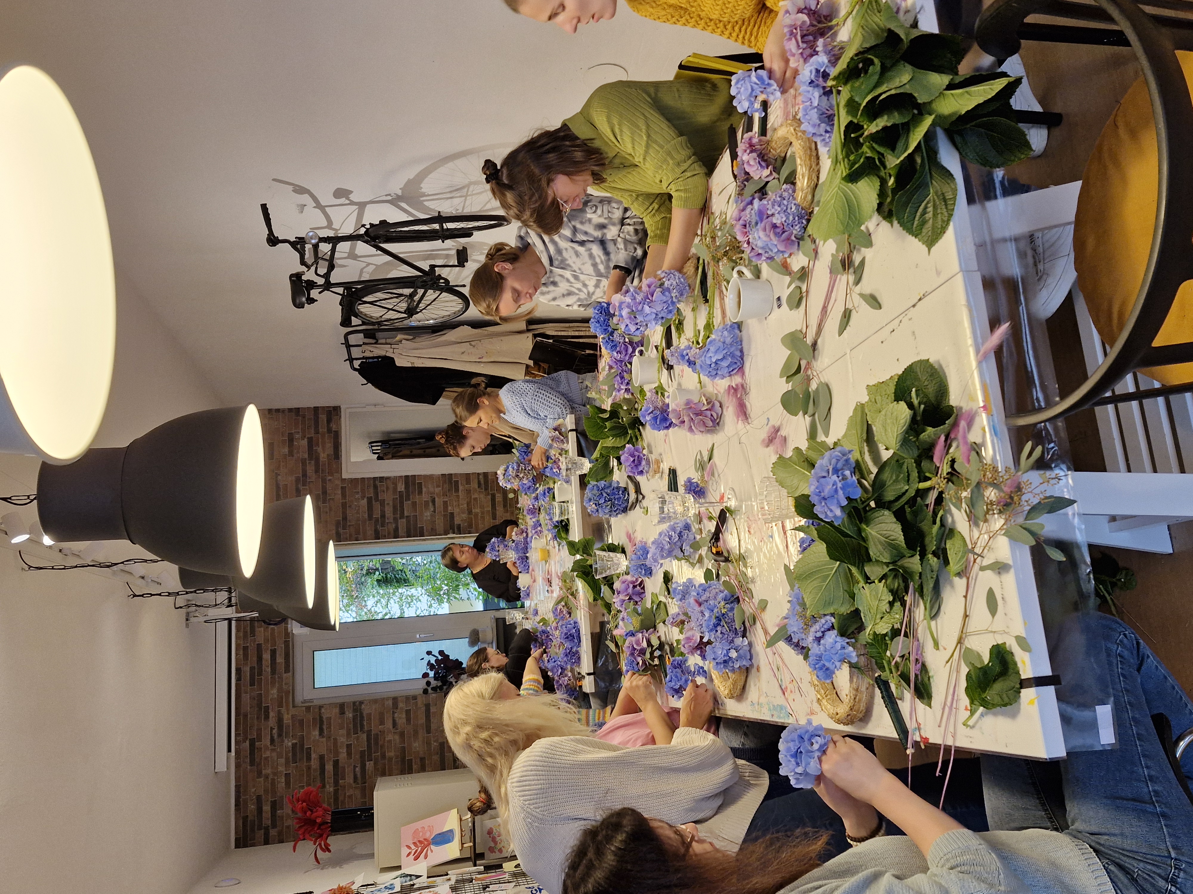 Personen basteln Blumenarrangements an einem Tisch.