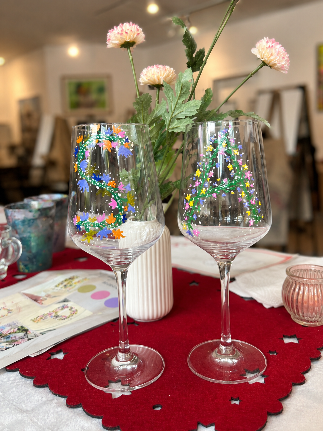 Two painted wine glasses on red tablecloth.