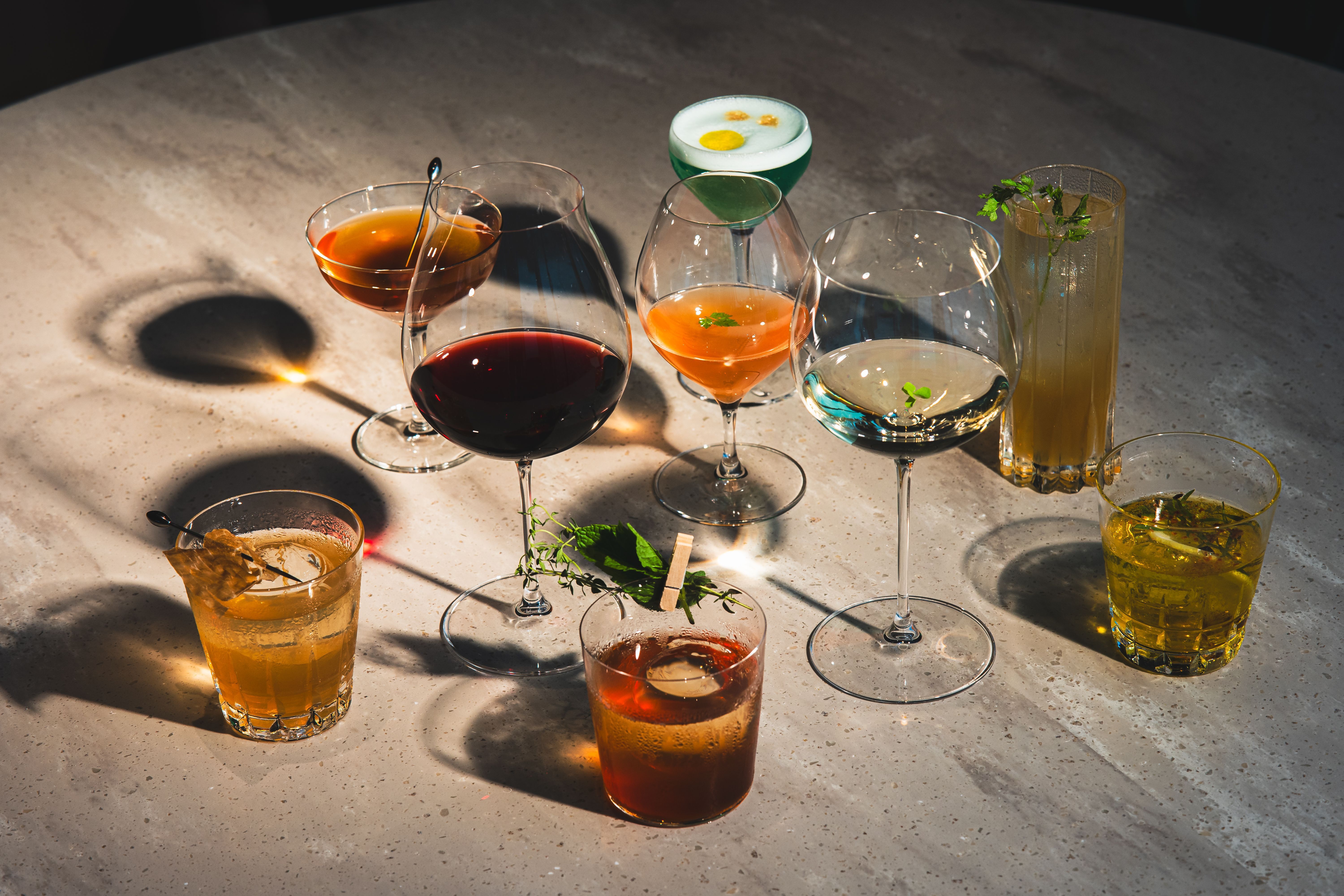 Acht verschiedene Cocktails auf einem Tisch.