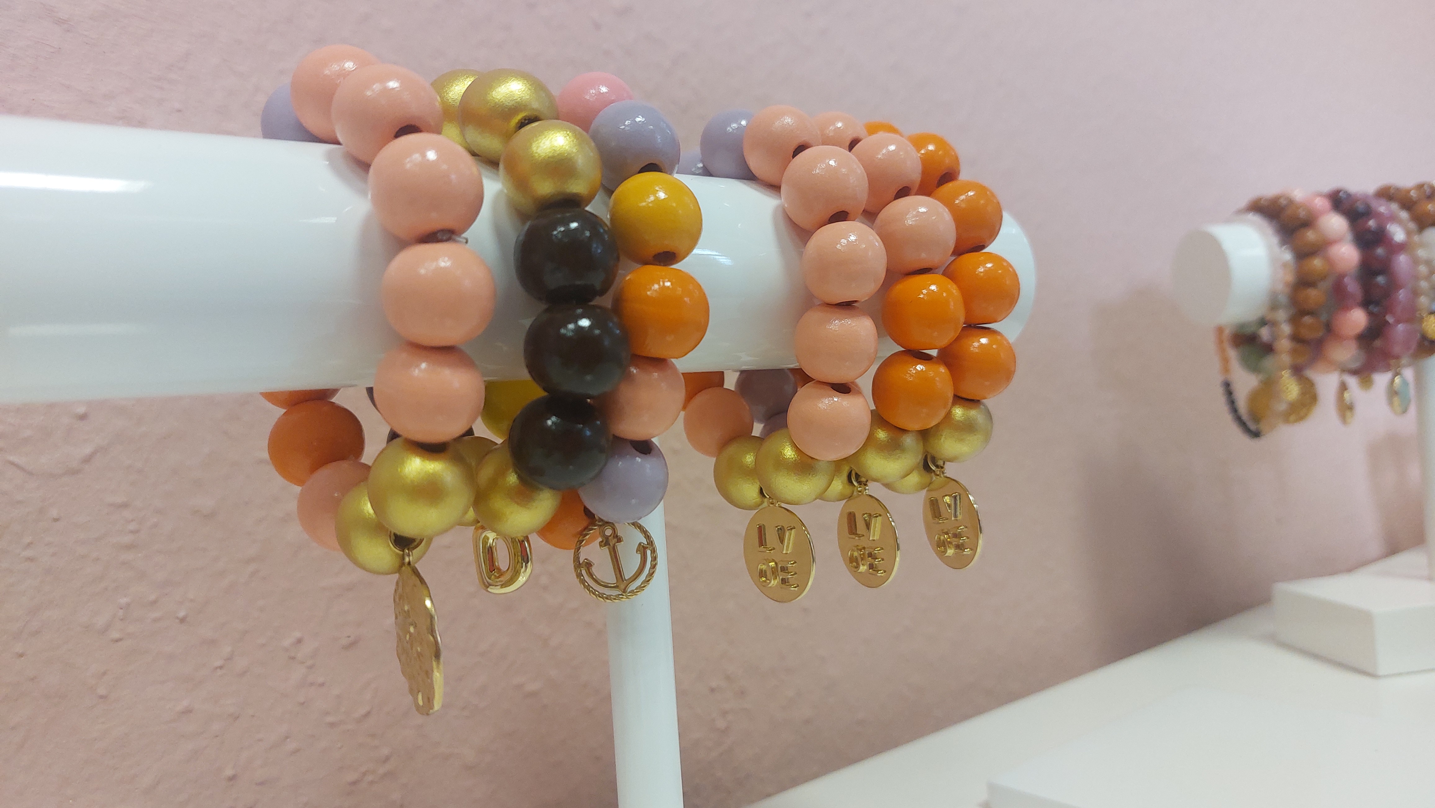 Bunte Perlenarmbänder auf einem weißen Ständer.