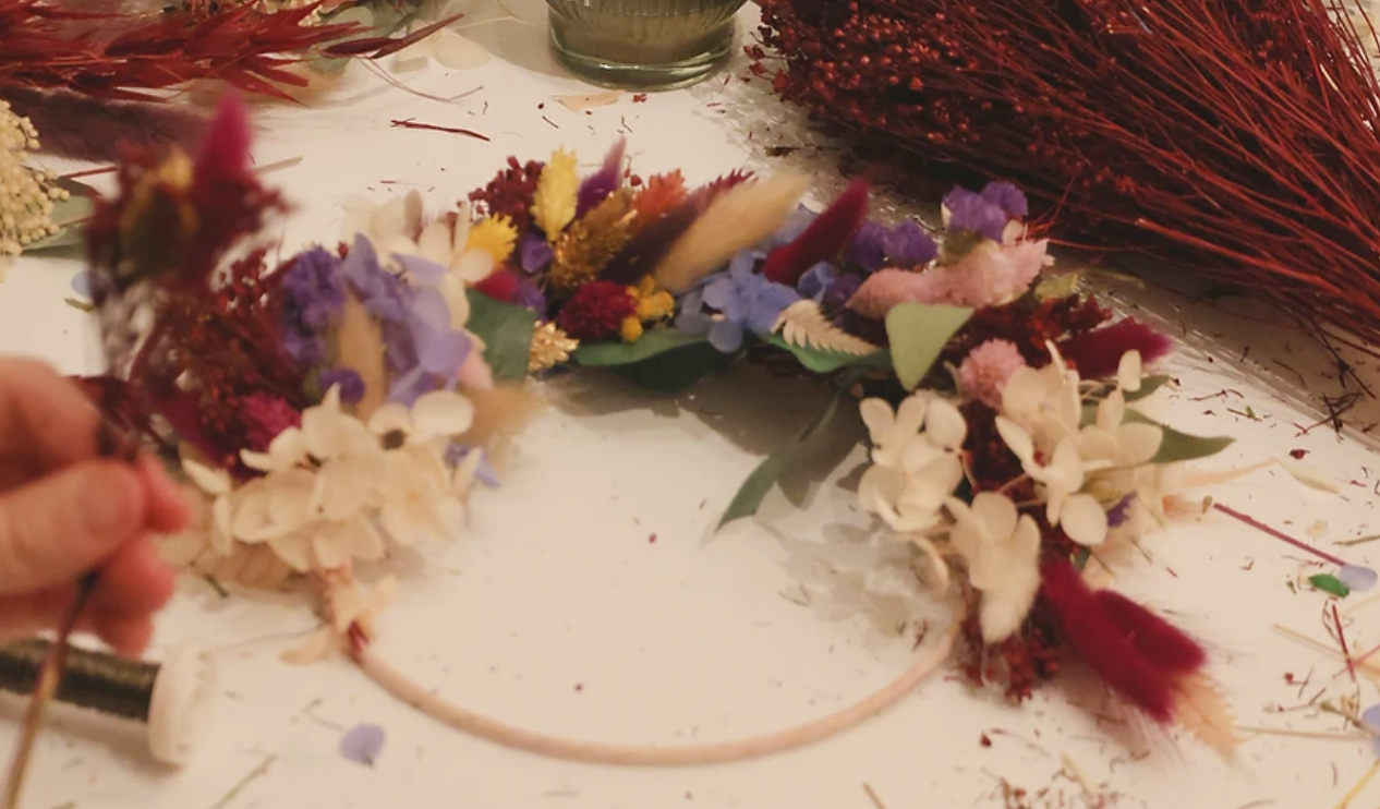 Kranz mit bunten Trockenblumen auf Tisch.