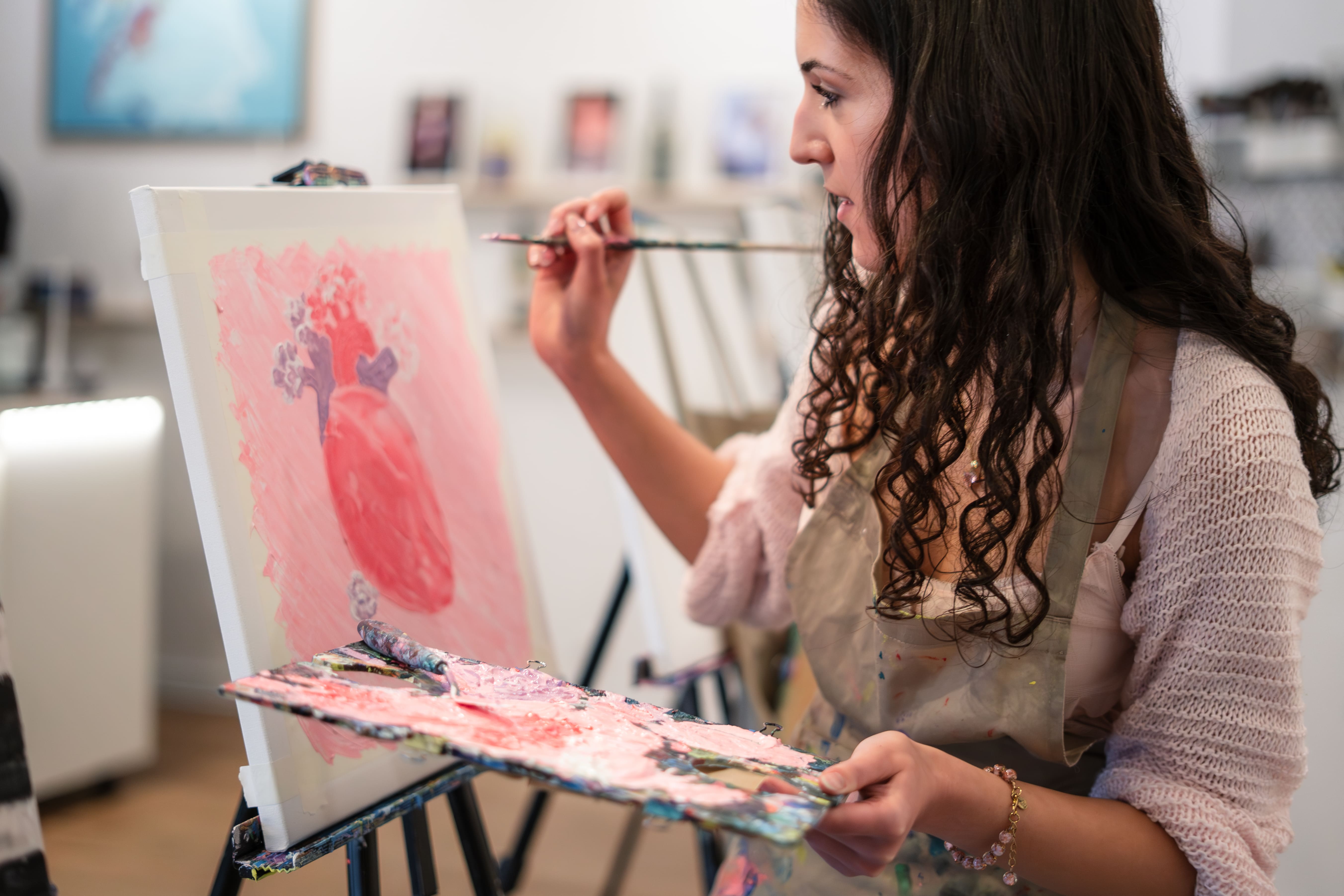 Woman painting heart on canvas in studio.