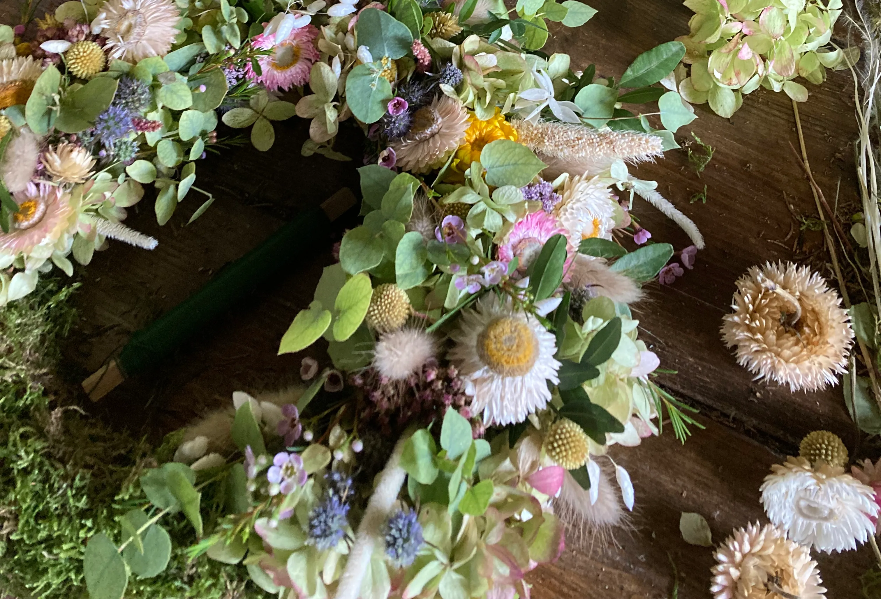 Floral wreath on wooden table with tools.