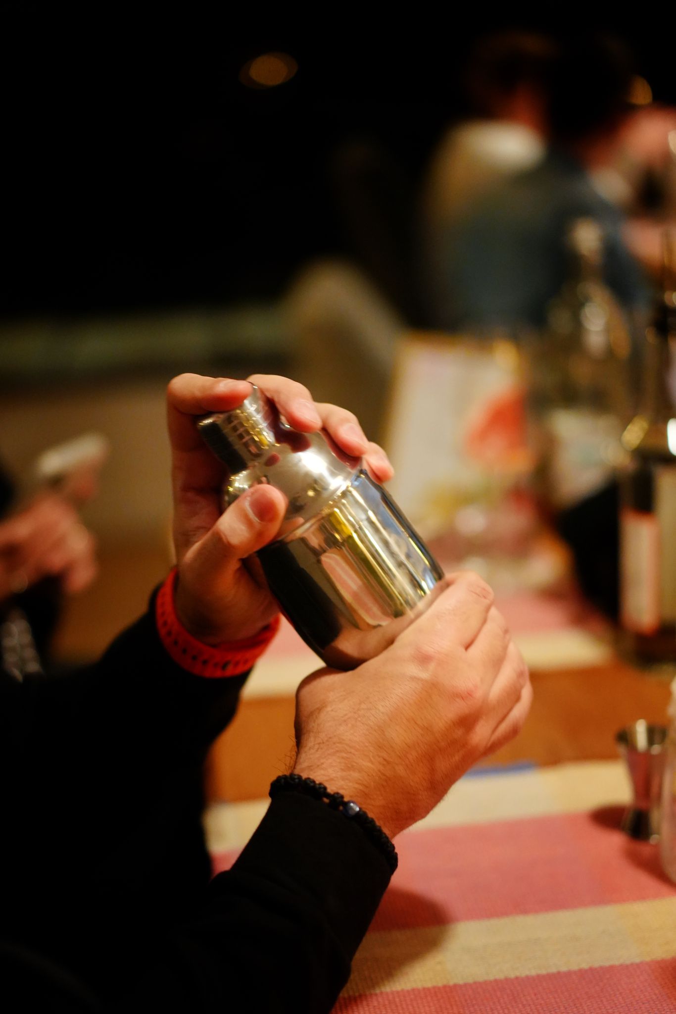 Person shaking cocktail shaker in bar.