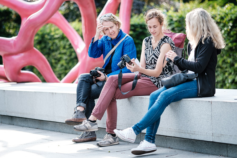 Drei Frauen sitzen und betrachten Fotos auf einer Kamera.