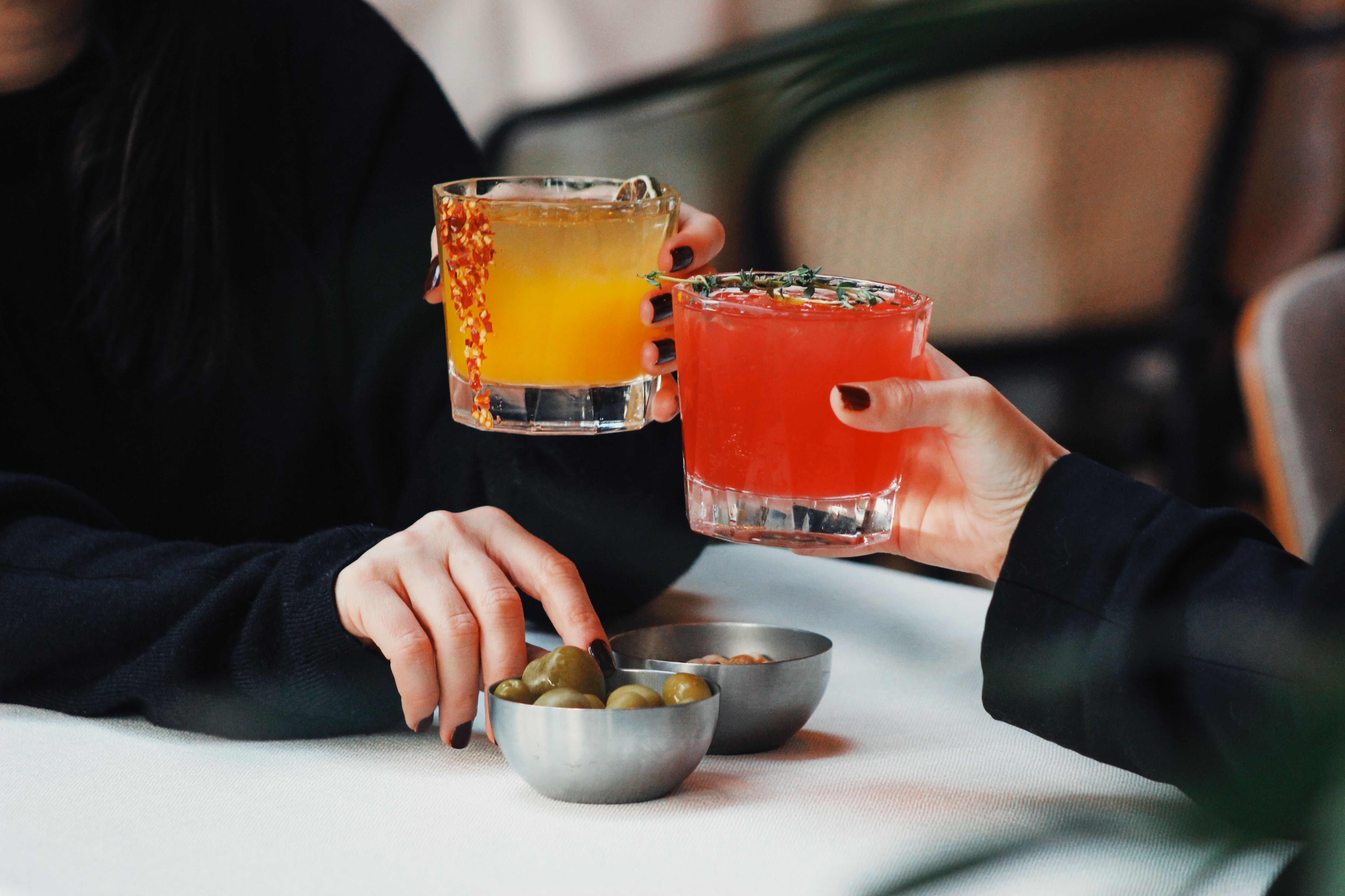 Two hands clinking glasses over table.