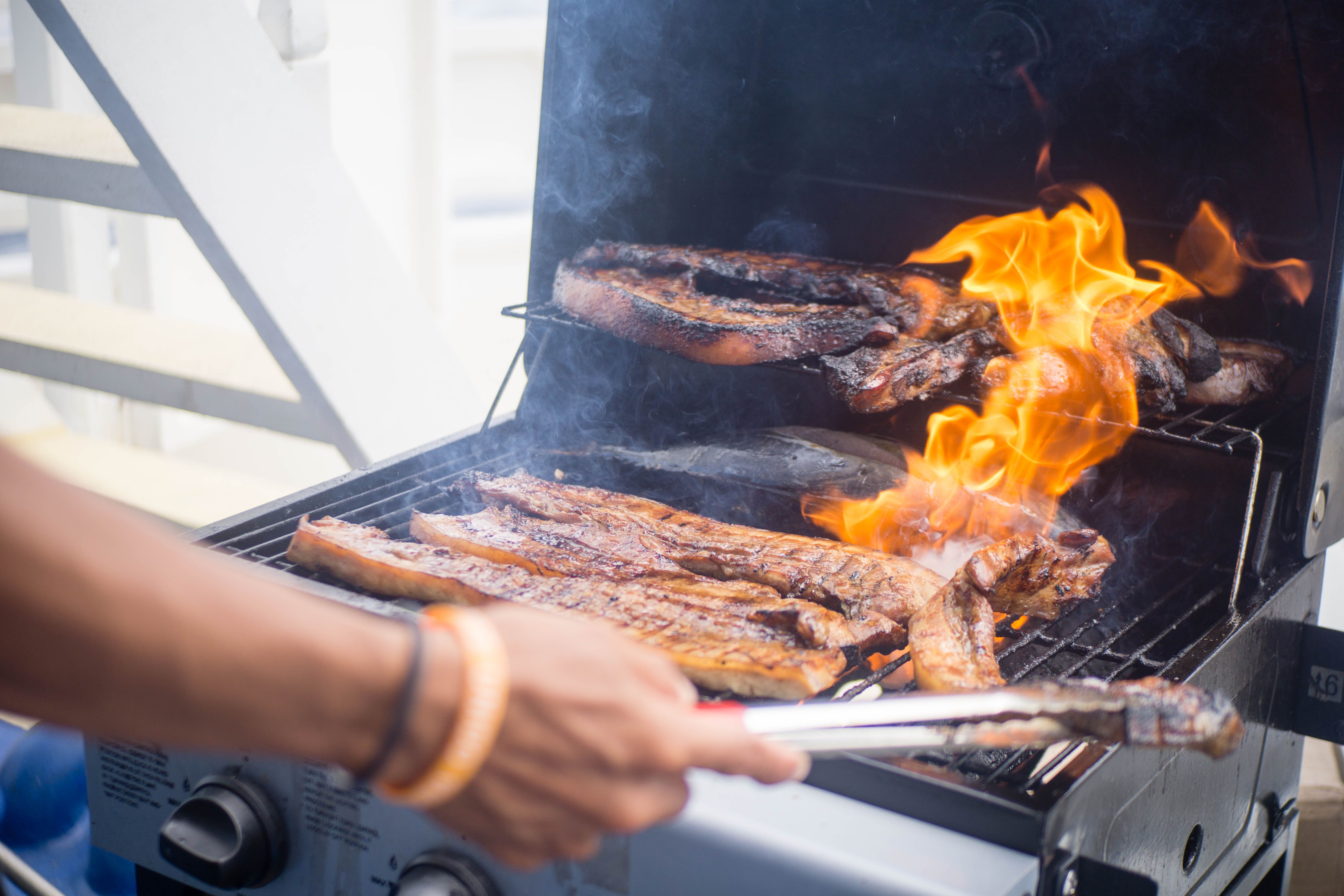 Grilled meat with flames on barbecue grill.