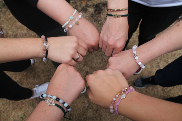Six people showing bracelets outdoors.