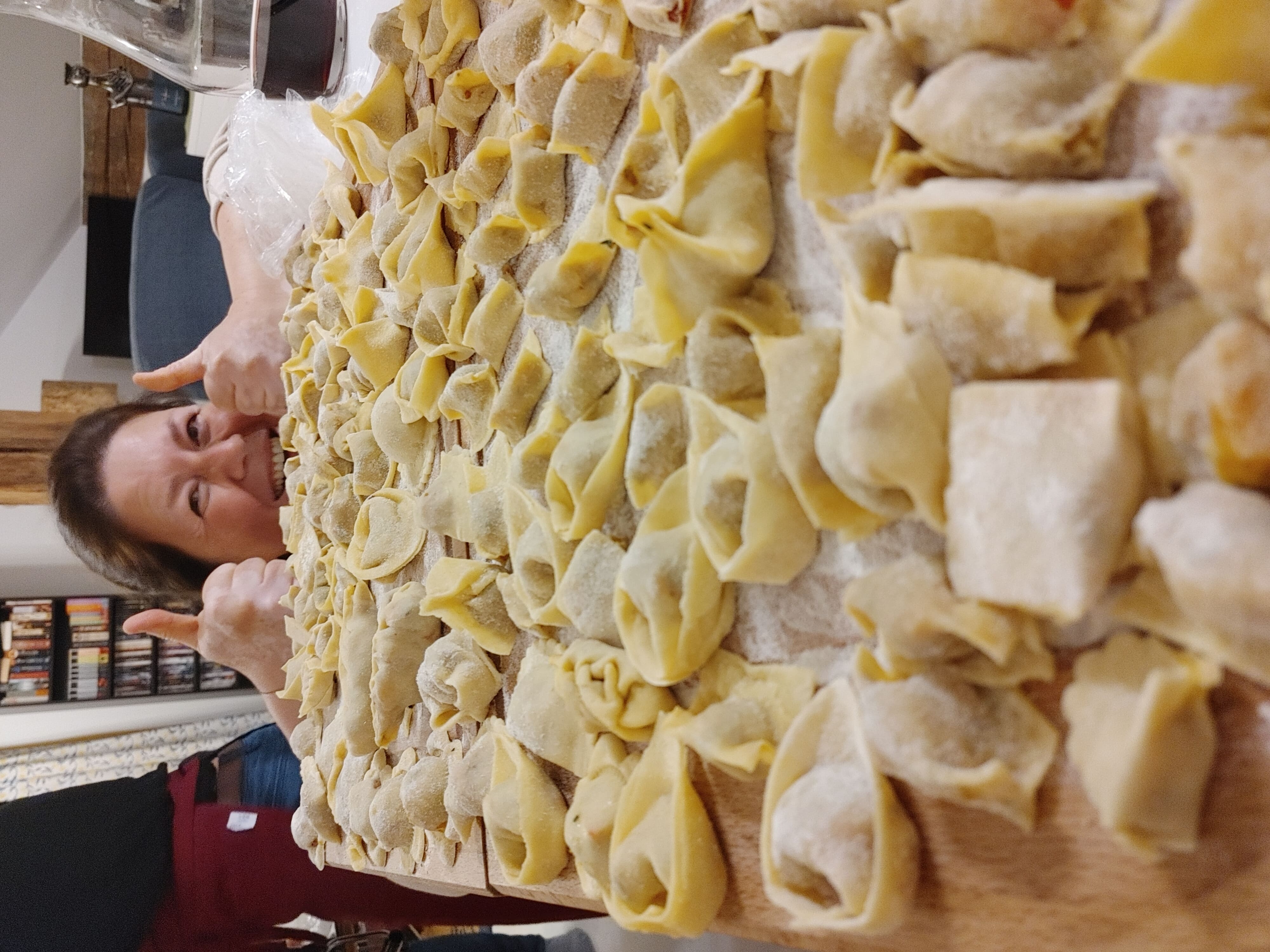 Frau zeigt Daumen hoch hinter hausgemachter Pasta.